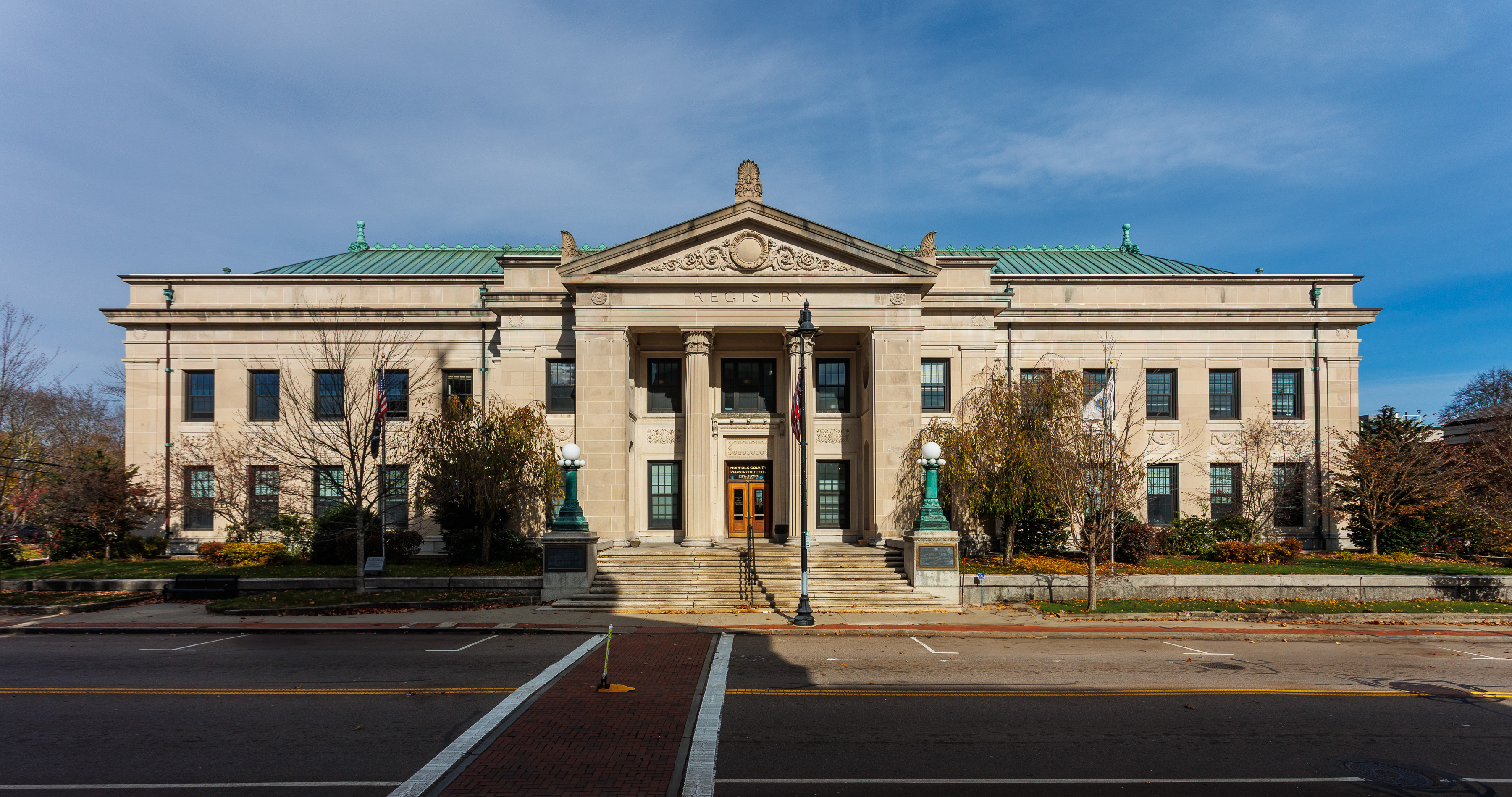 Neoclassical stone government building with green copper roof and columned entrance.