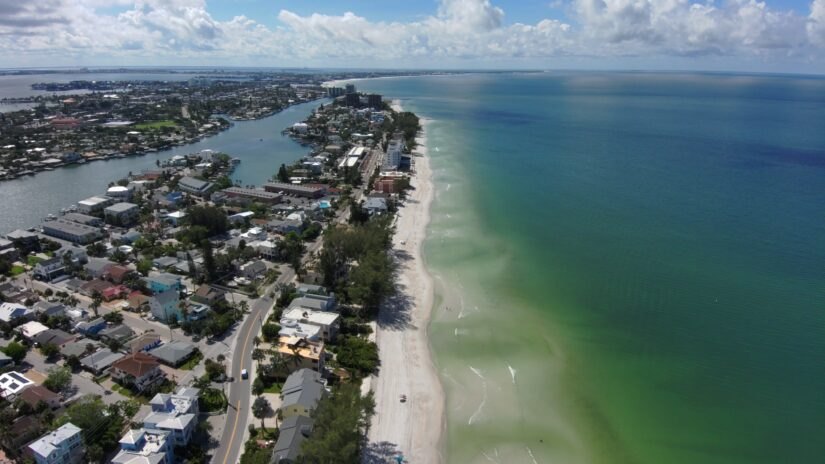 Aerial view of a narrow barrier island beach with Gulf waters and intracoastal waterway.