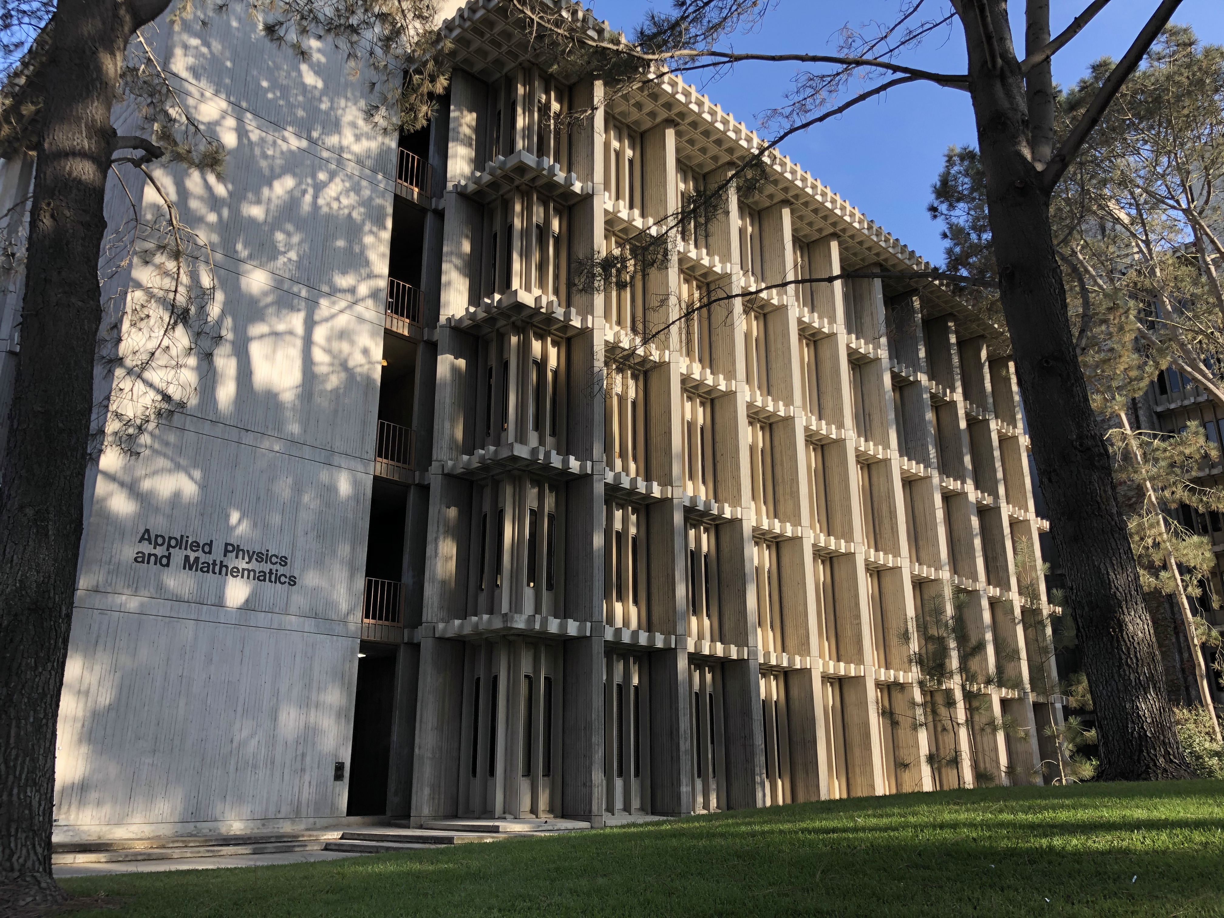 Modernist concrete academic building on the UC San Diego campus surrounded by trees.