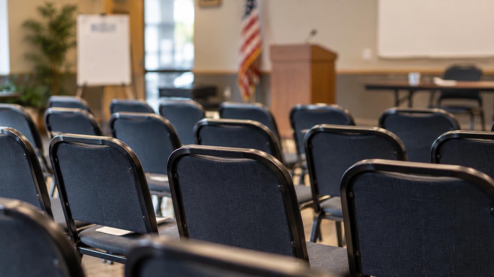Rows of empty chairs arranged in a community meeting room.
