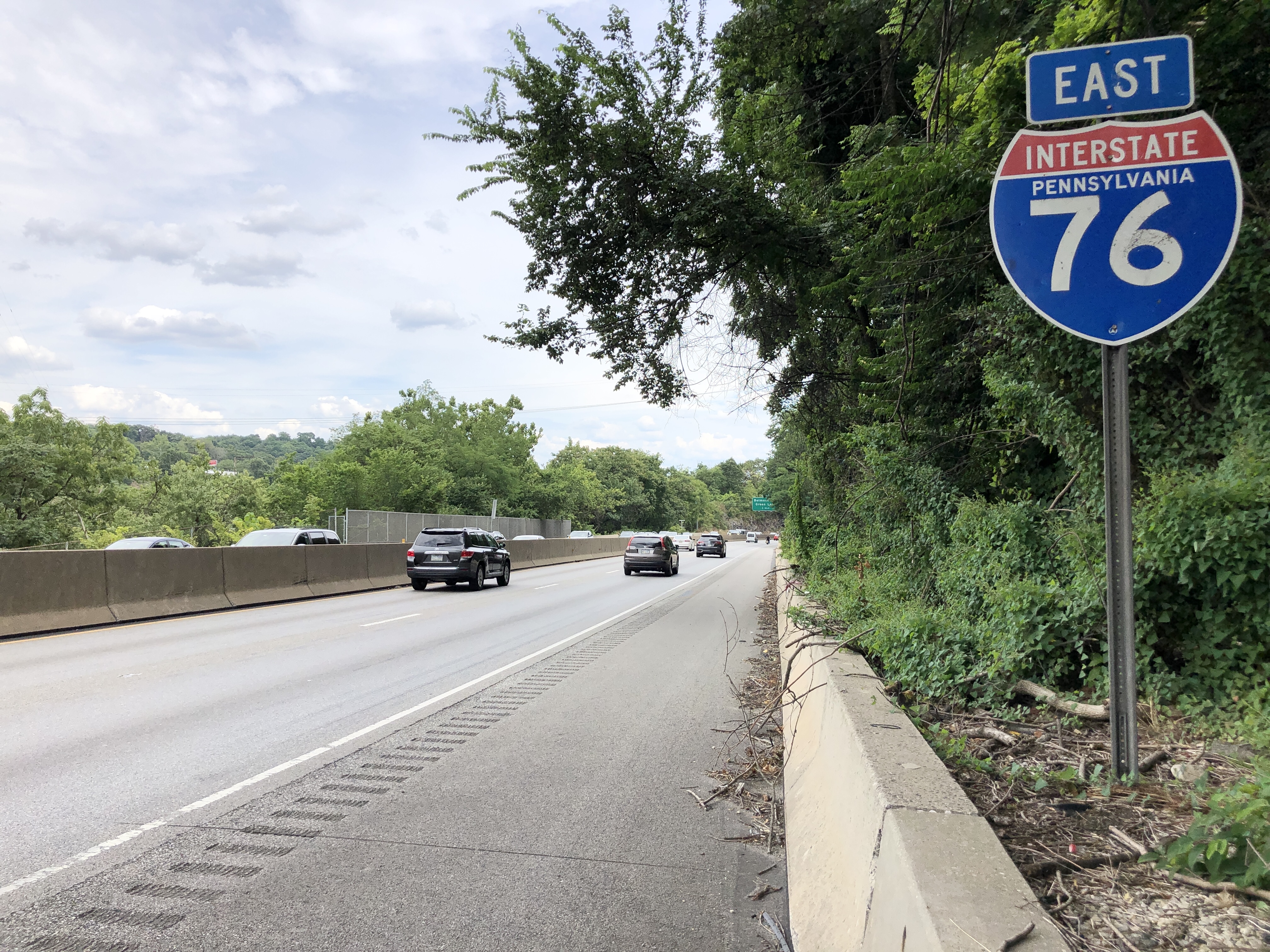 Eastbound lanes of Interstate 76 in Lower Merion Township with moving traffic and highway signage.