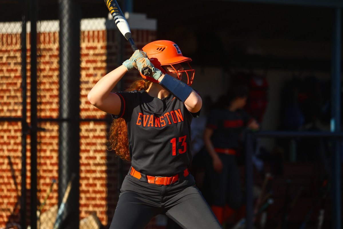 Softball player in an Evanston jersey and orange helmet stands in a batting stance.