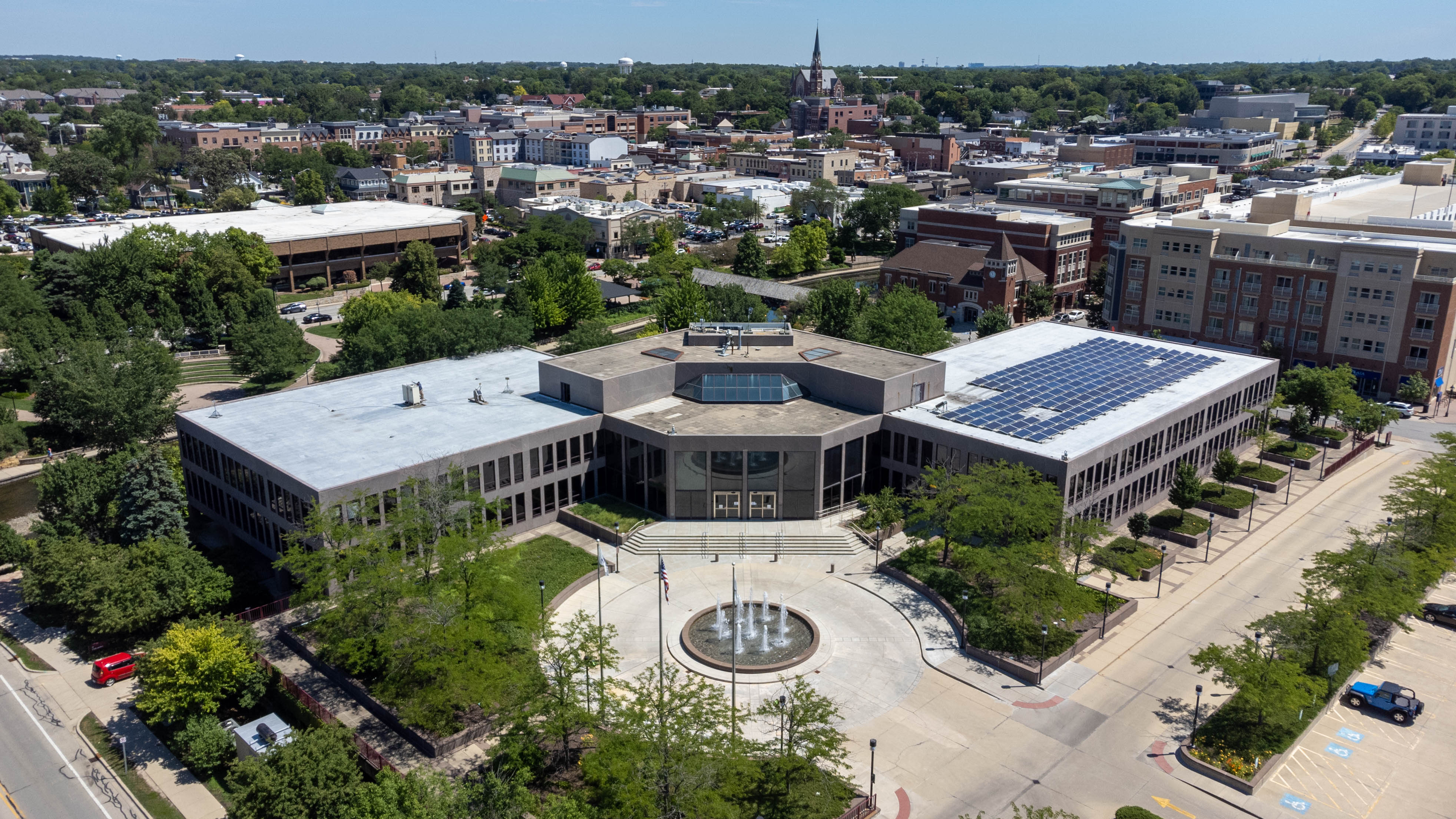 Aerial view of a large civic building complex with a circular fountain plaza.