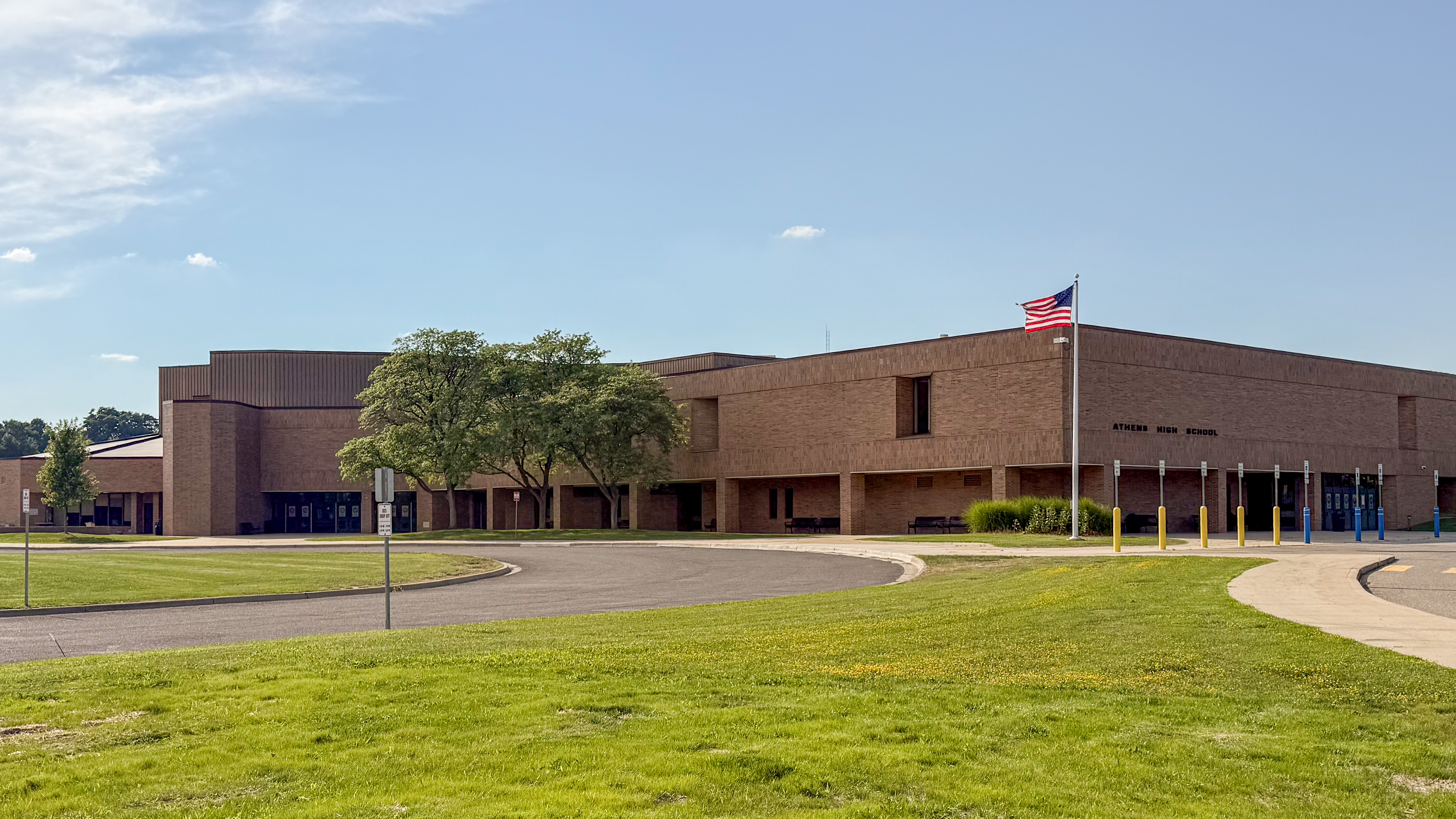 Large brick school building with an American flag and paved circular driveway.