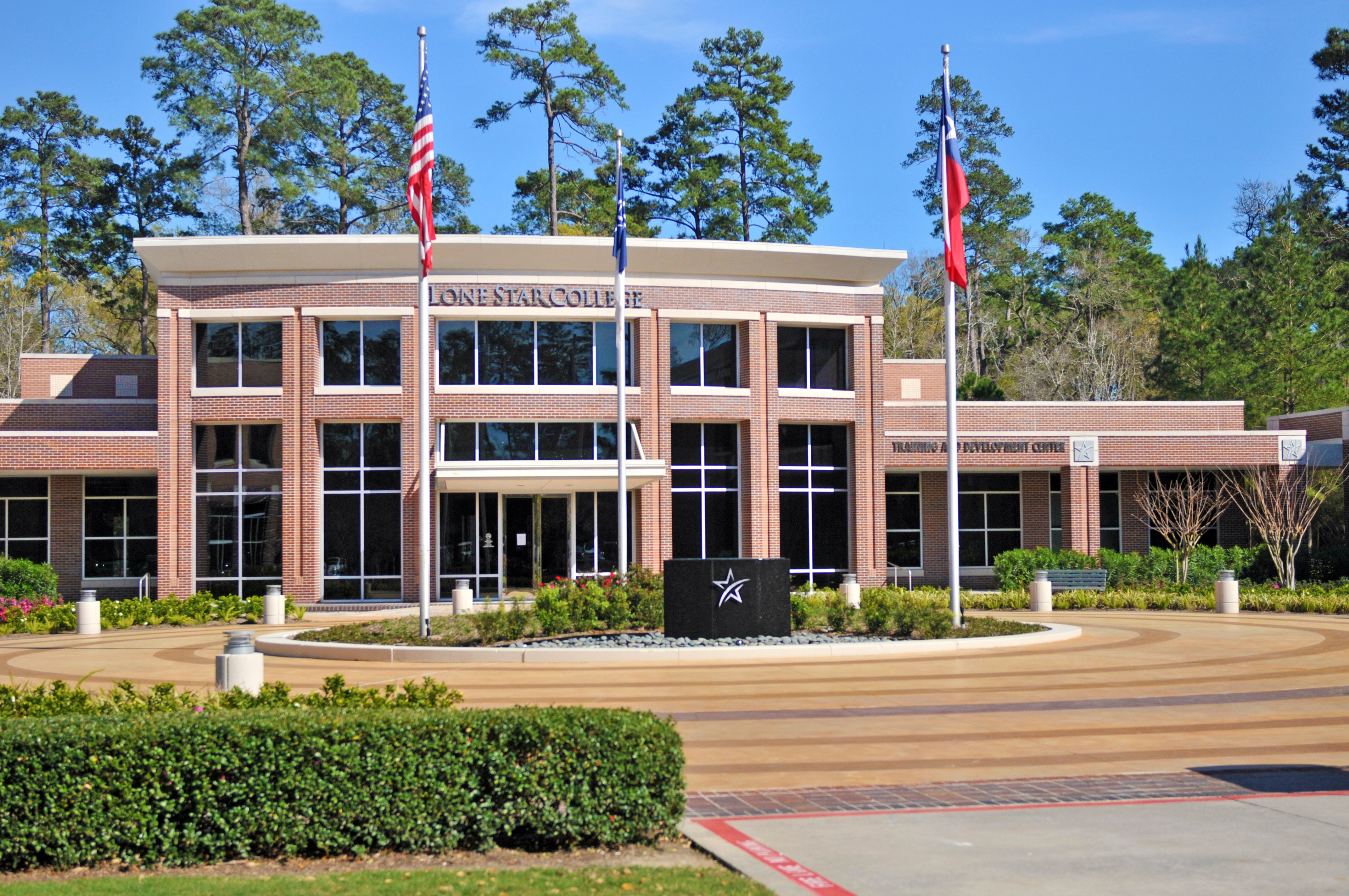 Two-story brick college building with flagpoles and a star-logo monument sign at the entrance.