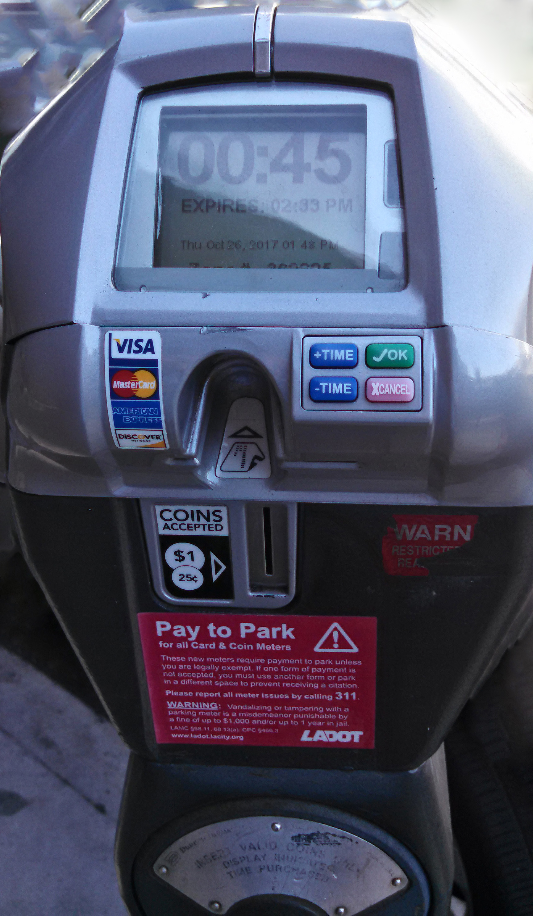 A gray digital pay-to-park kiosk displaying time remaining and payment options.