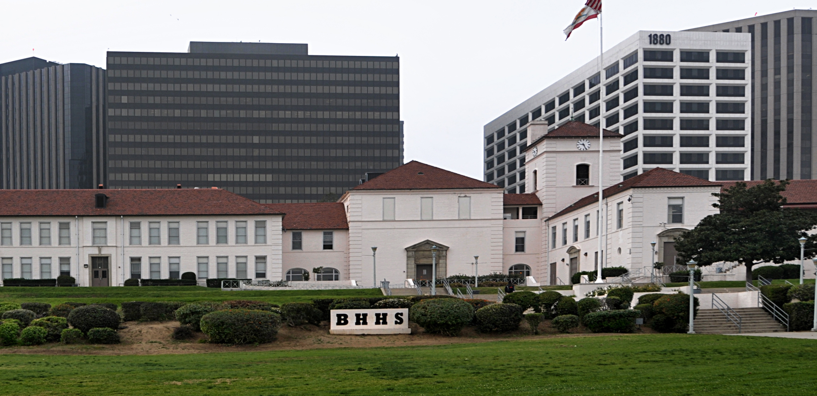 Exterior of Beverly Hills High School with white buildings, red tile roofs, and a BHHS sign.