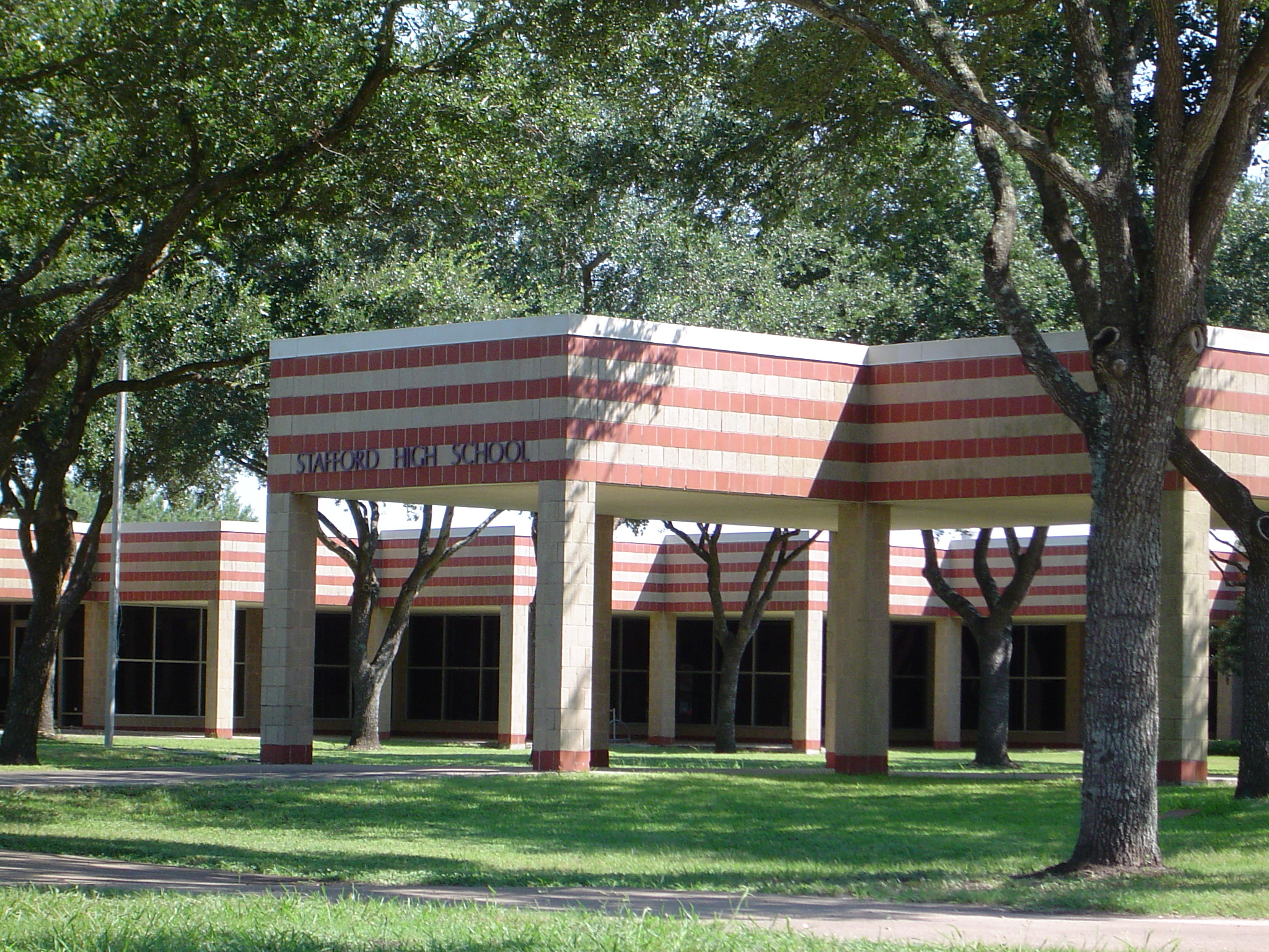Exterior of a school building with red and beige striped facade and columns.