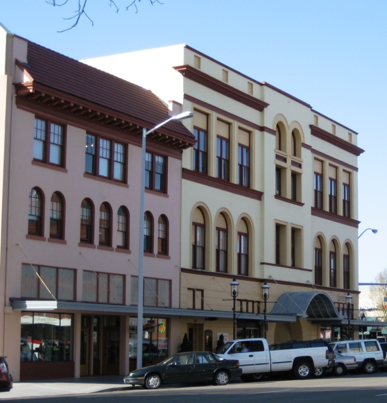 Historic two-story building with cream facade, arched windows, and a canopied entrance.
