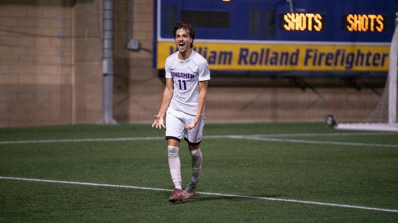 Soccer player in white Kingsmen number 11 jersey celebrates with arms spread wide.