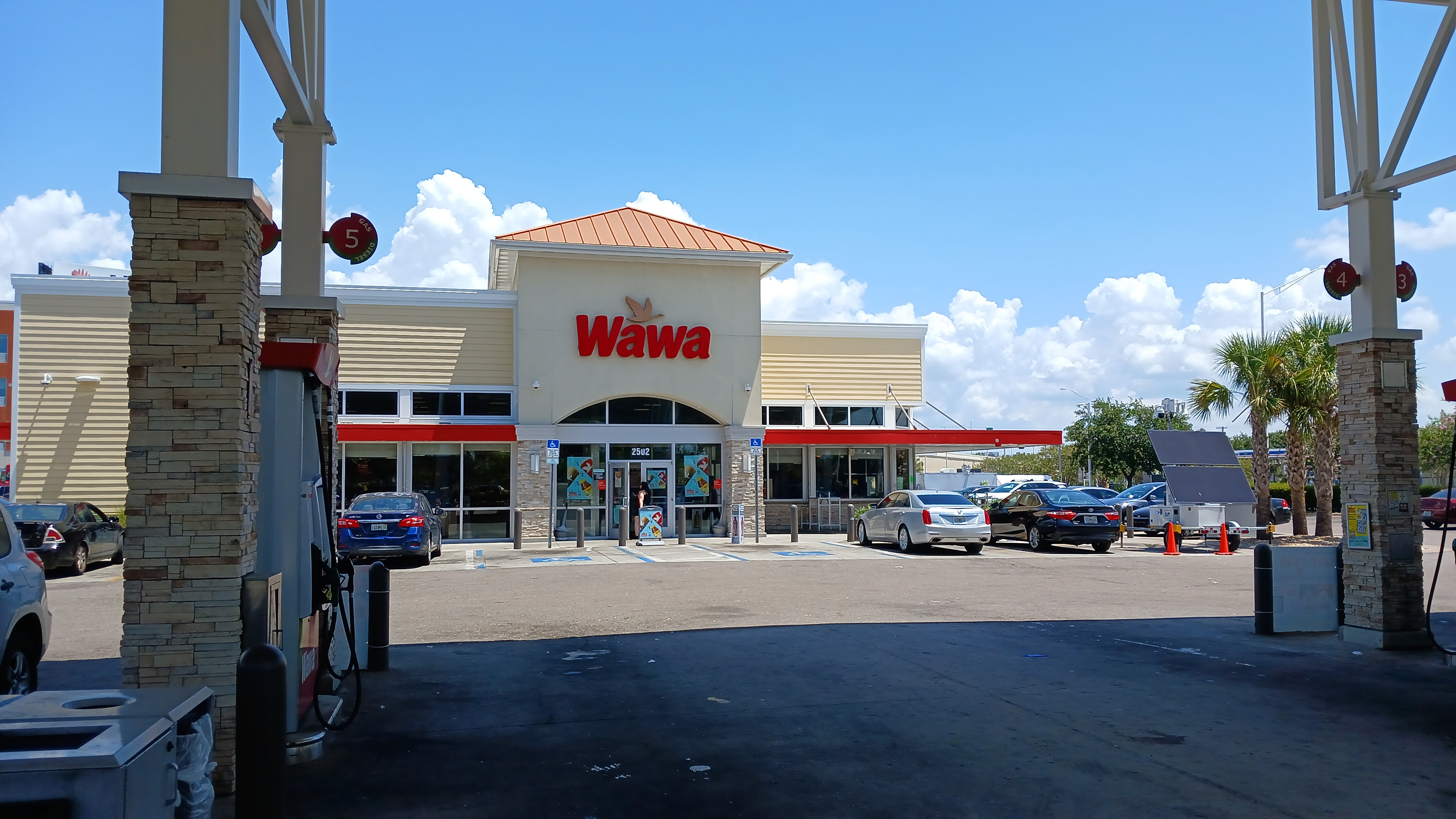 Wawa convenience store exterior with fuel pumps and blue sky.