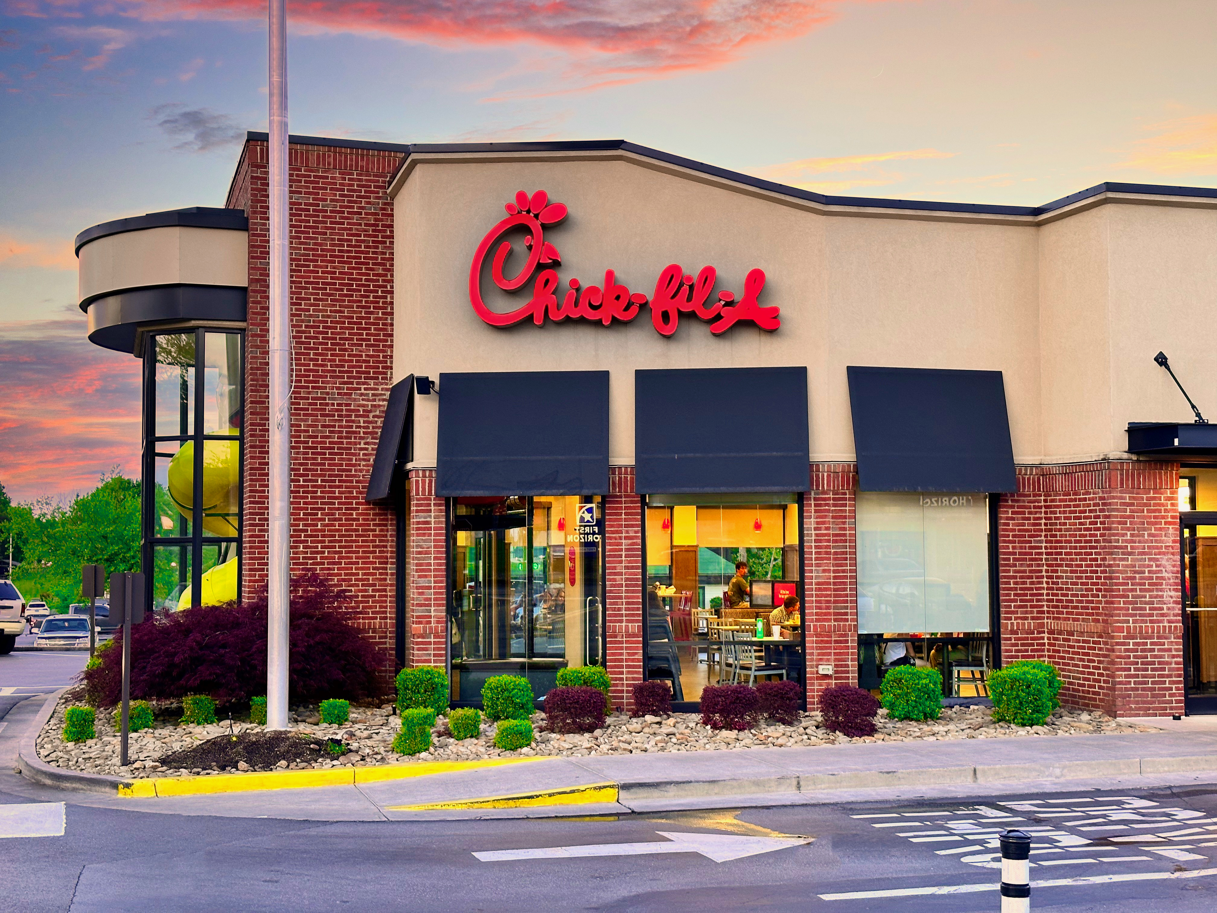 Chick-fil-A restaurant exterior with brick facade, black awnings, and red logo at dusk.