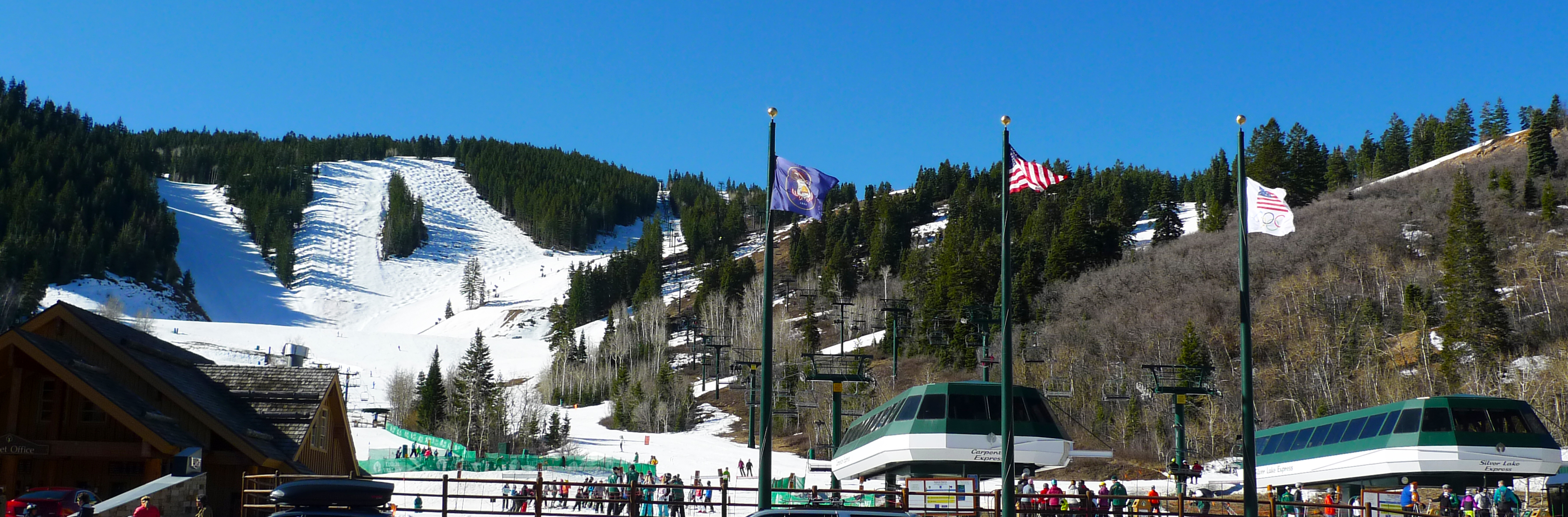Snow-covered ski runs and chairlifts on a mountain slope under a clear blue sky