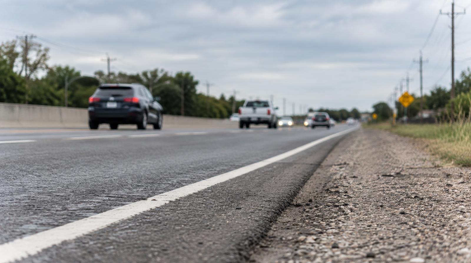 Empty multi-lane highway with white lane markings receding into the distance.