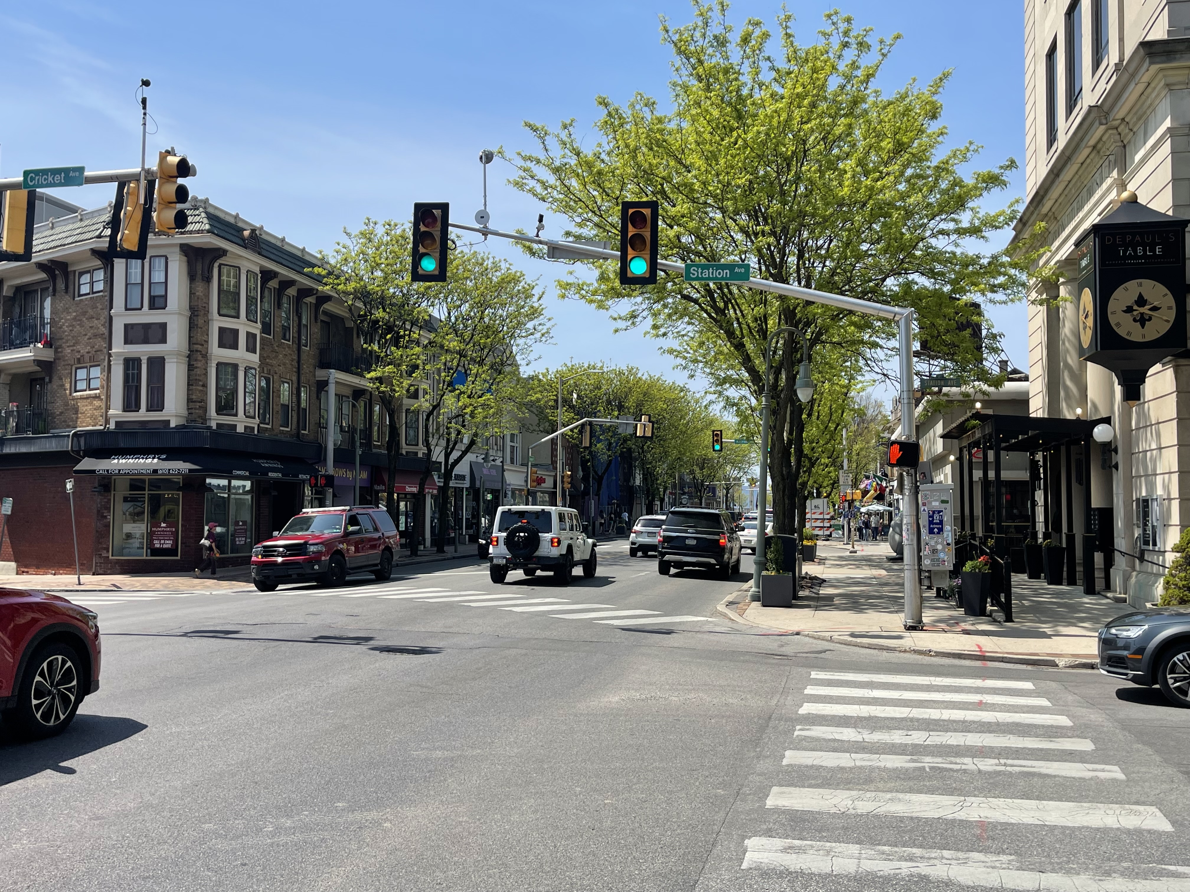 Busy commercial intersection on Lancaster Avenue with traffic signals and storefronts.
