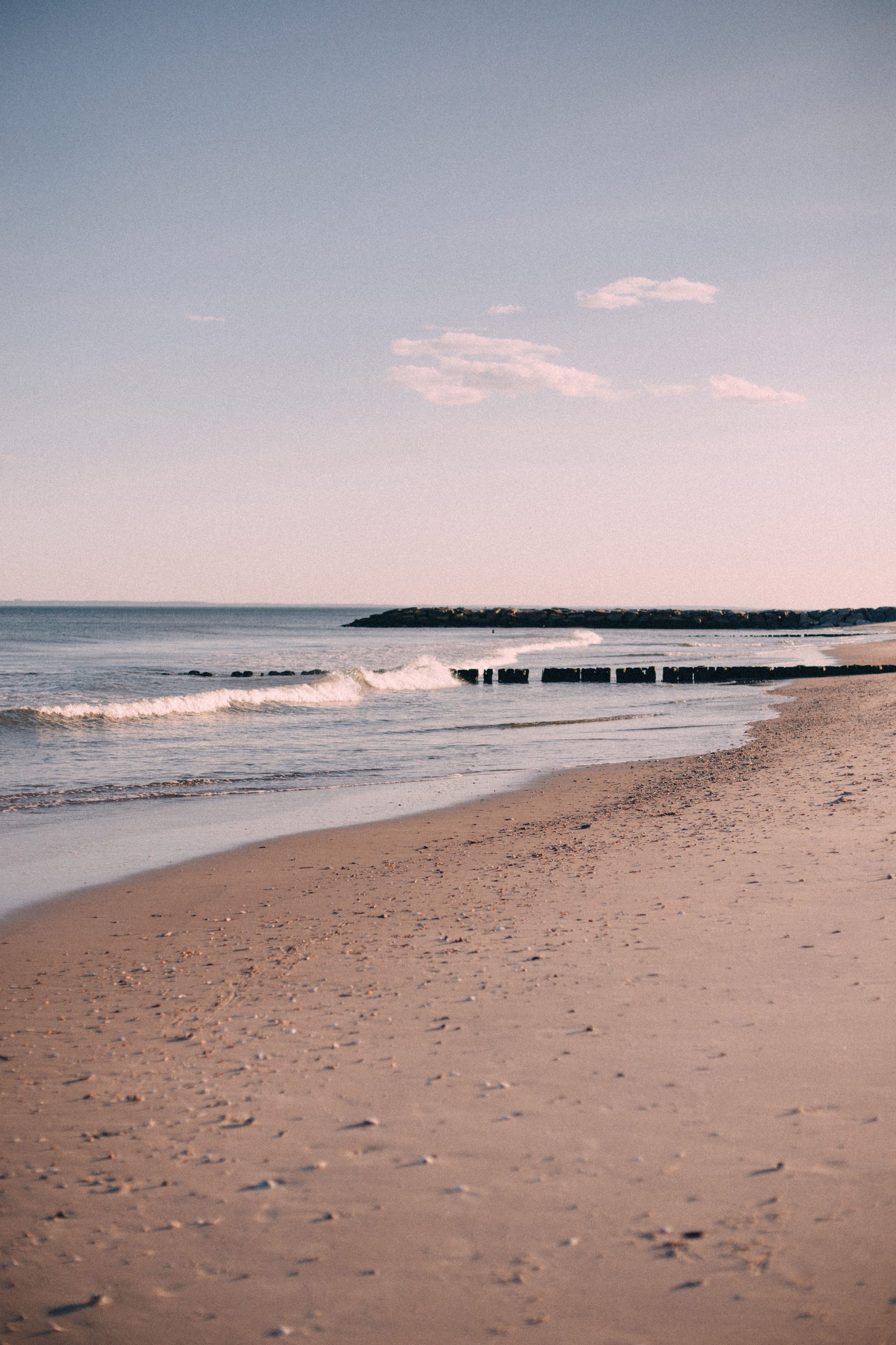 Tranquil sandy beach with gentle waves and clear sky in New York City.