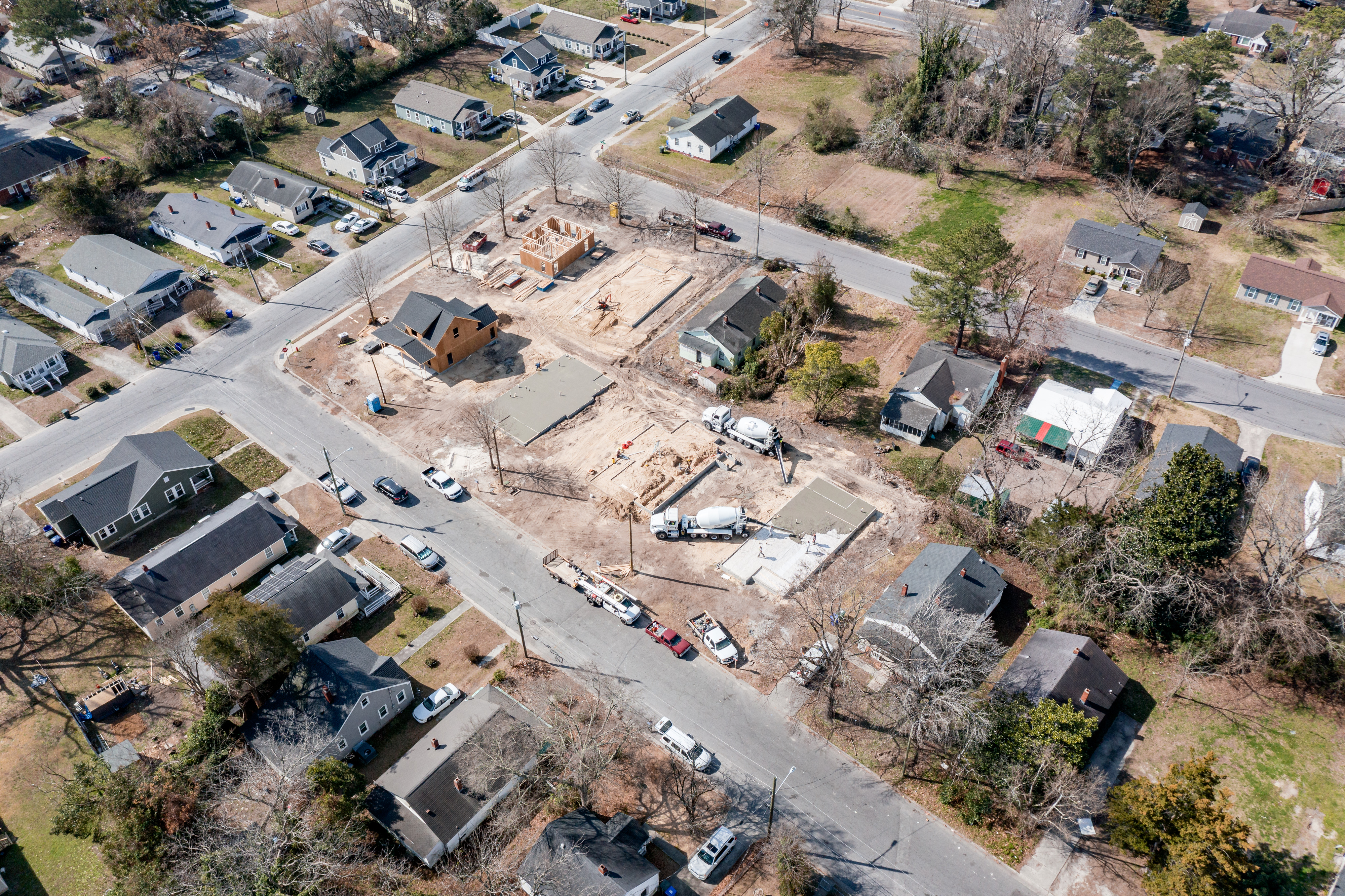 Aerial view of multiple homes under construction with wood framing and foundations visible.