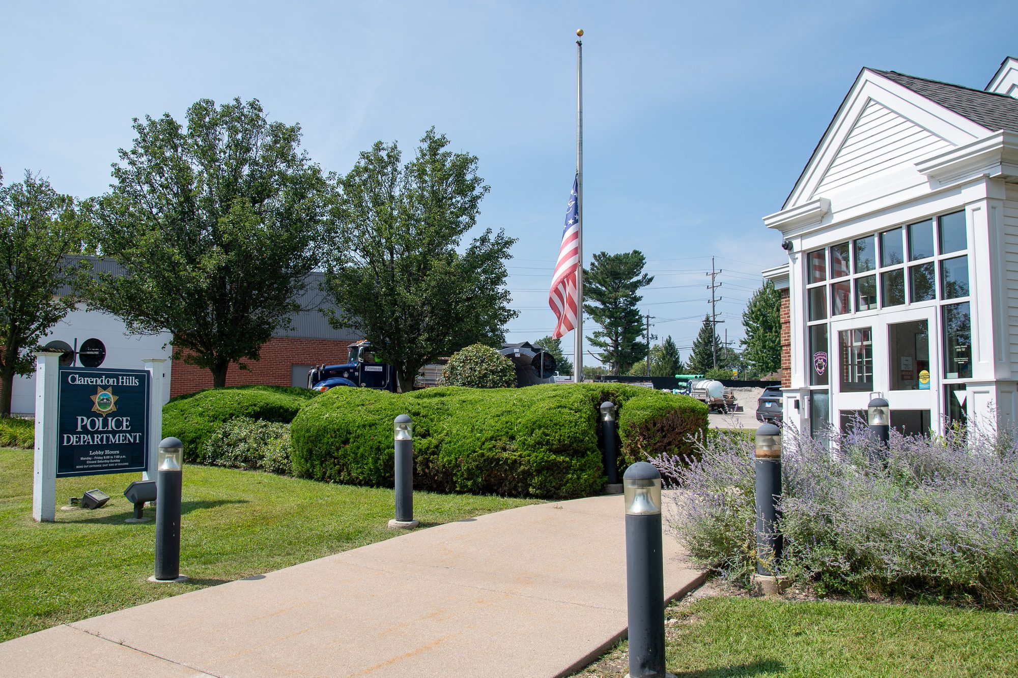 Exterior of a police department building with a flagpole and bollard-lined walkway.