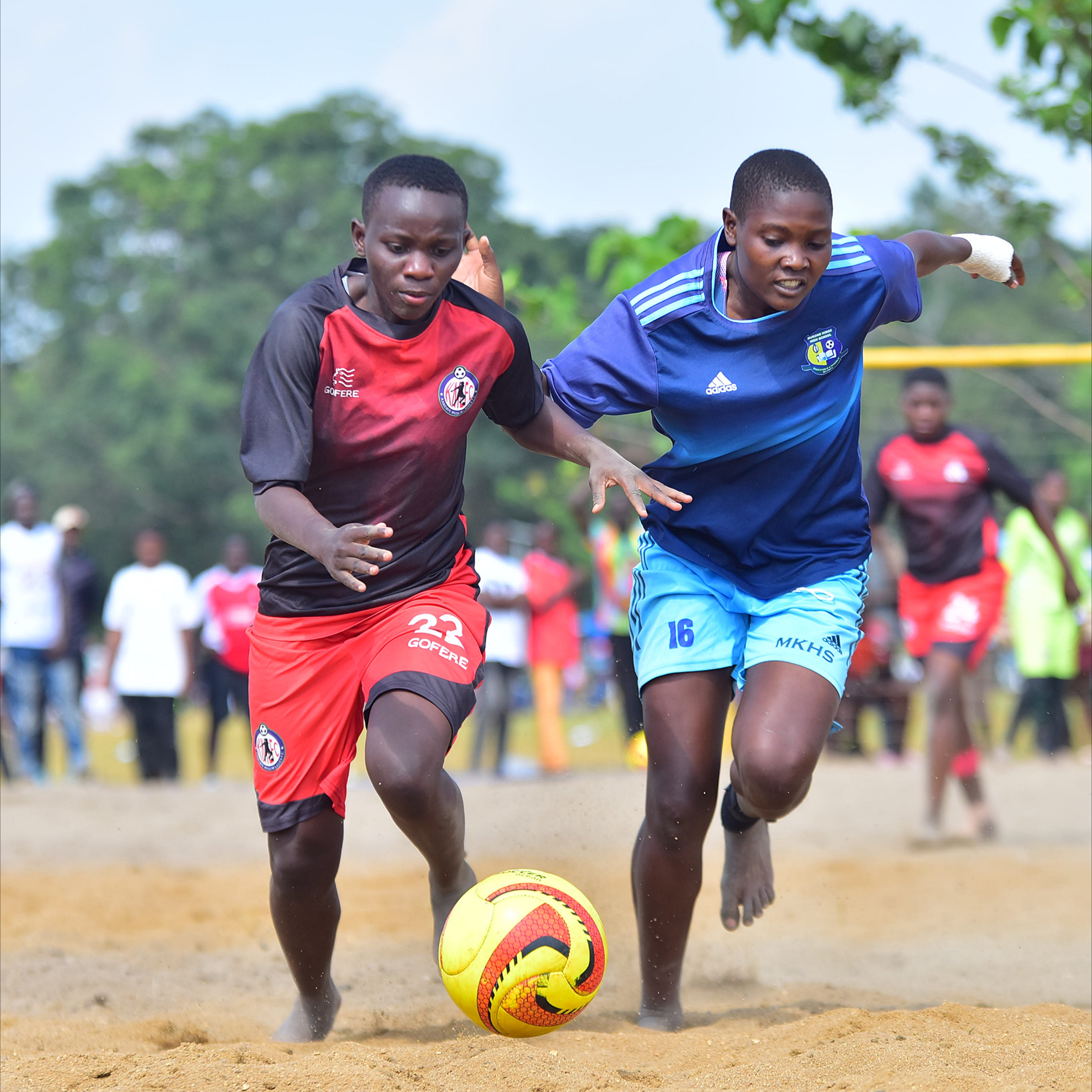 Two female soccer players compete for possession of a ball on a field.