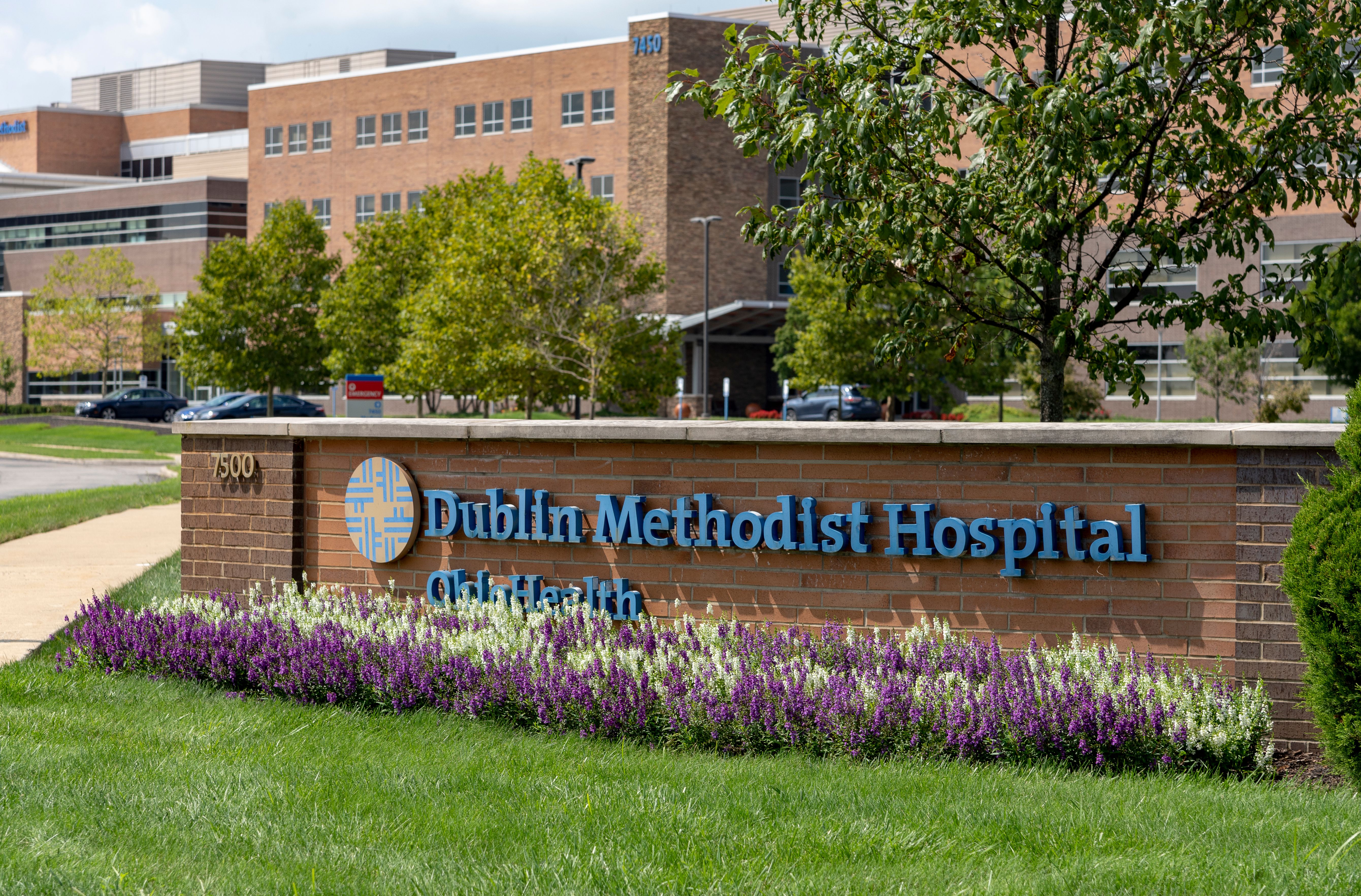 Brick entrance sign for Dublin Methodist Hospital with OhioHealth branding and flowering plants.