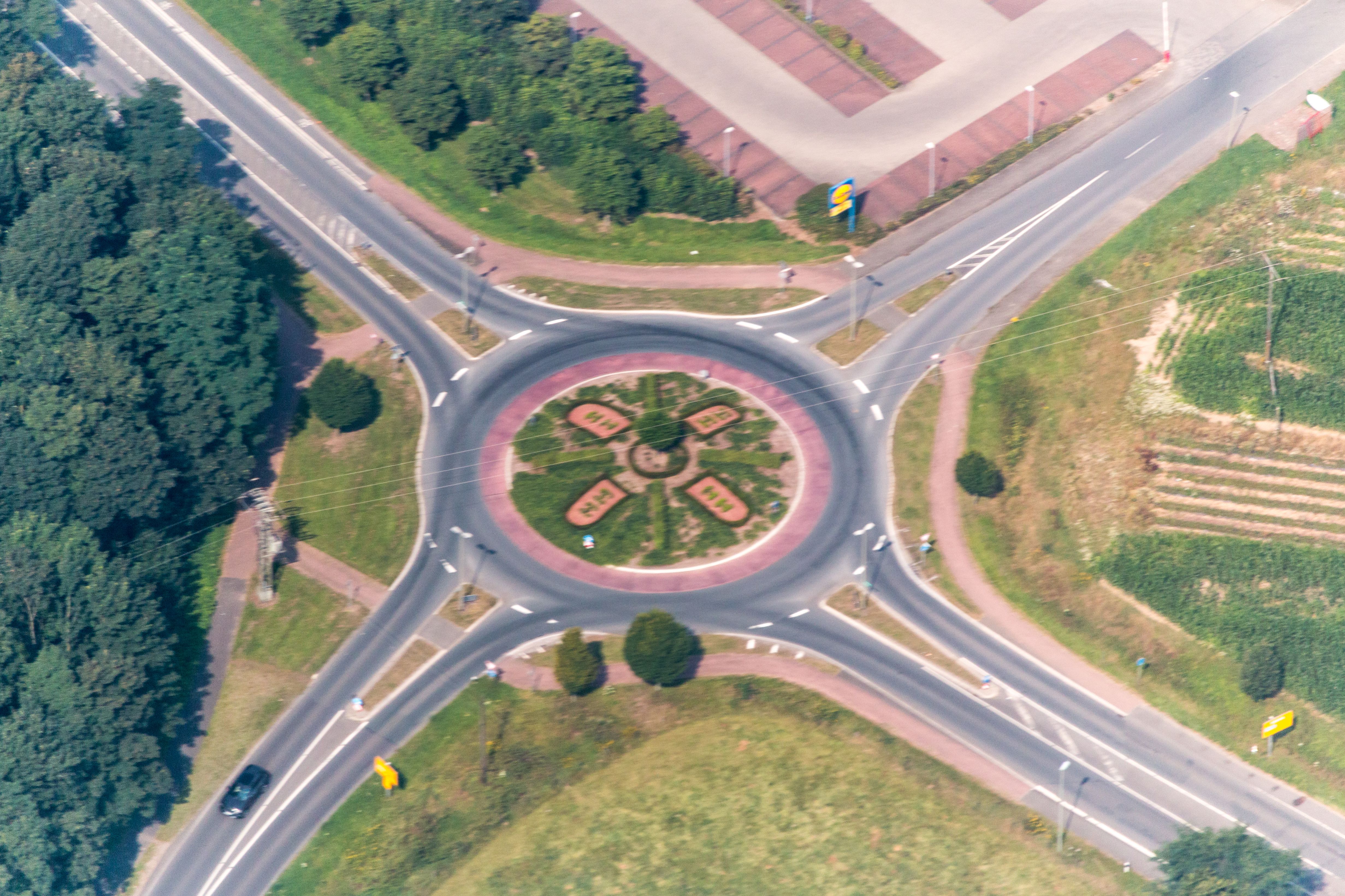 Aerial view of a four-way roundabout with a green landscaped center island.