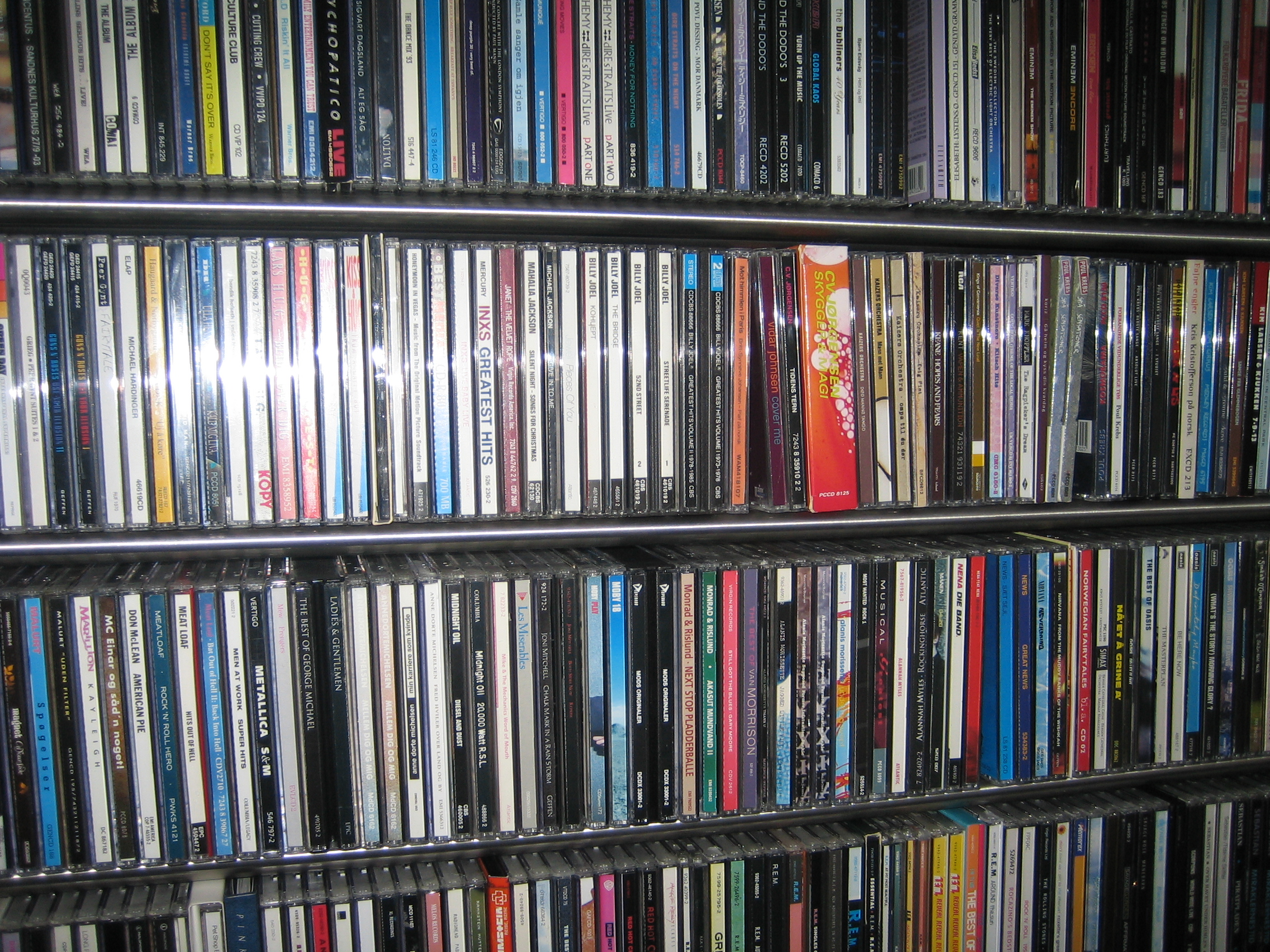 Hundreds of music CDs arranged upright on multiple metal shelving units.