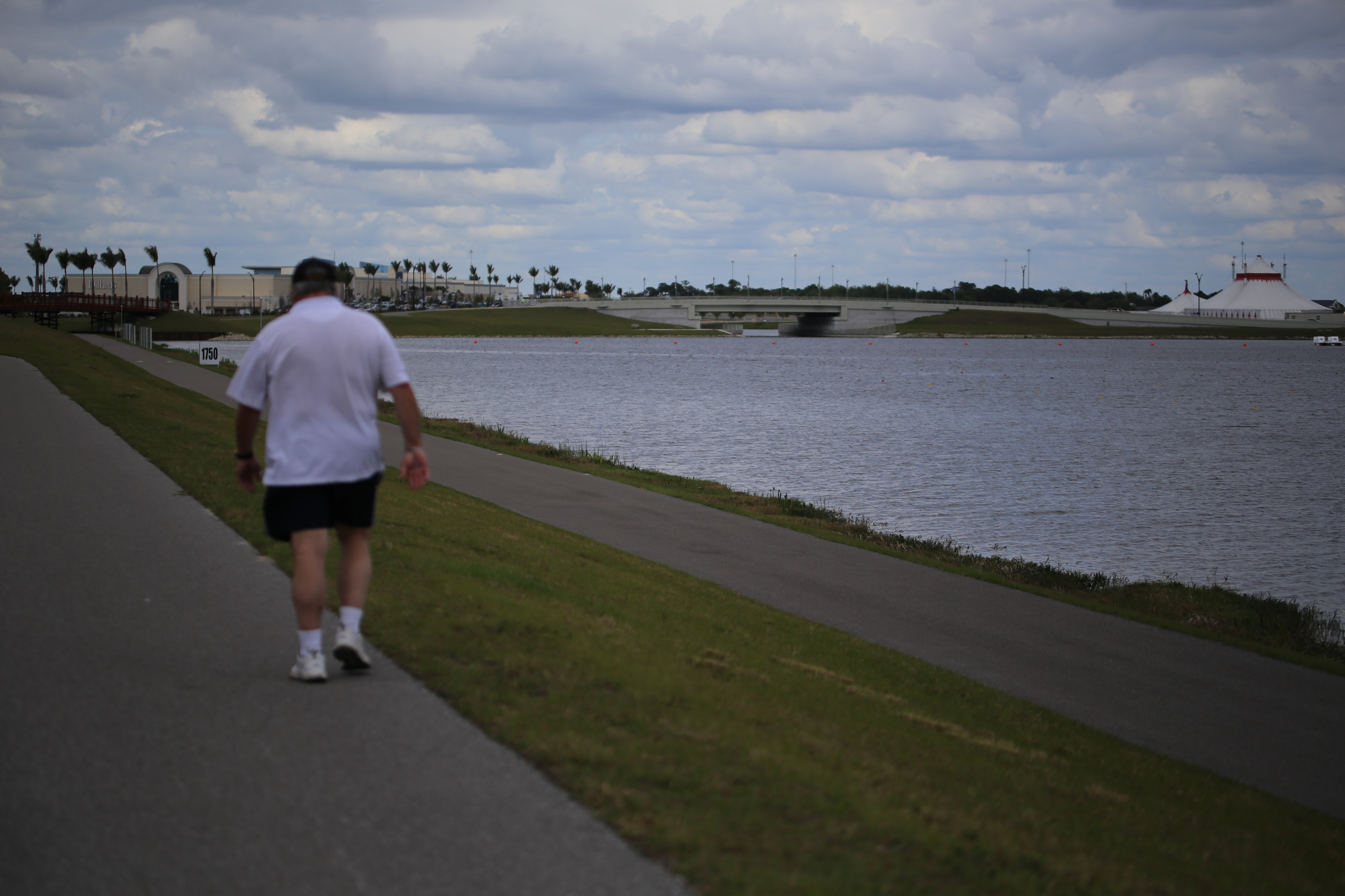 Person walking a paved path beside a lake at Nathan Benderson Park.
