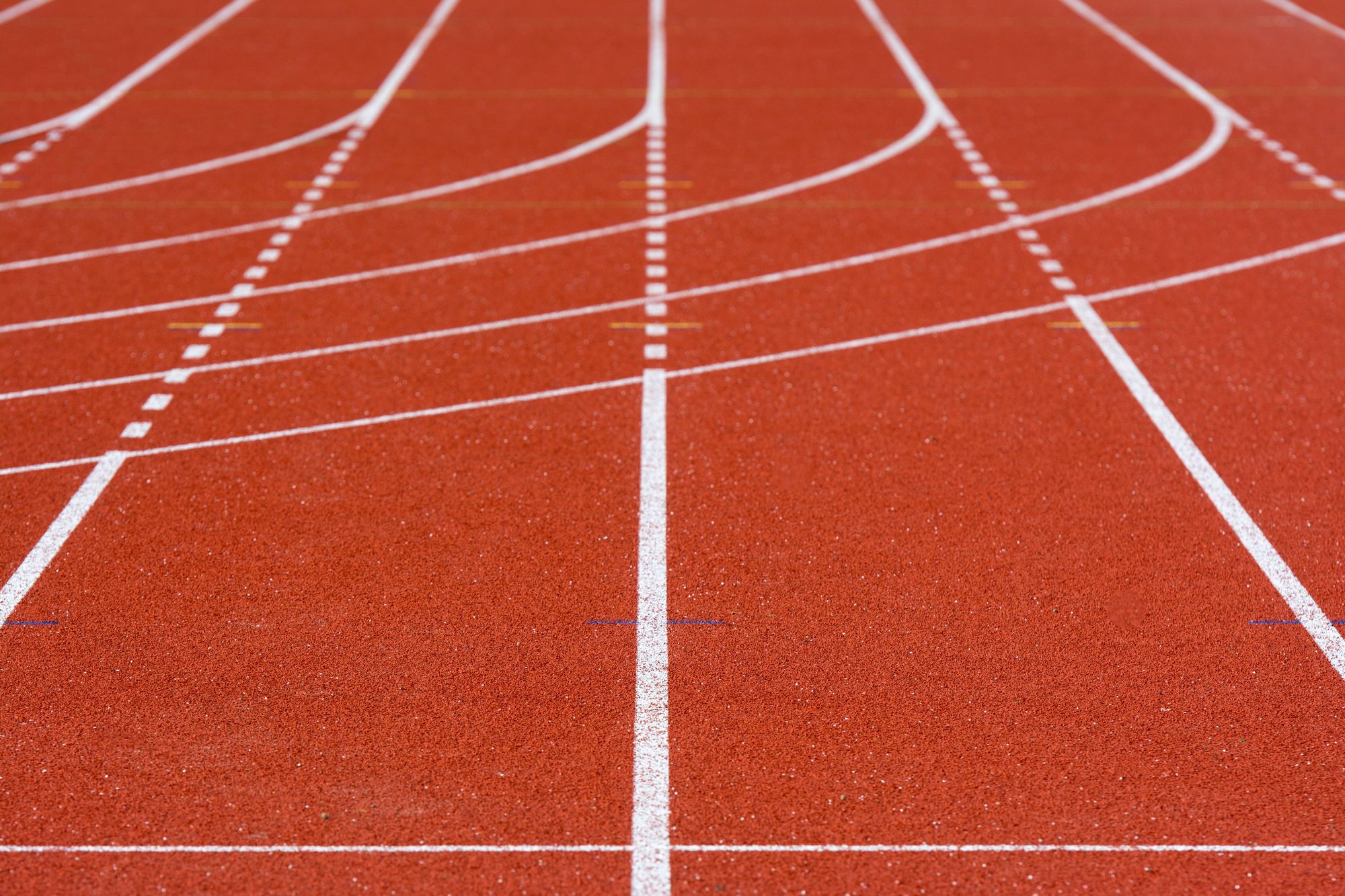A detailed view of an empty red running track with crisp white lanes, perfect for athletics.