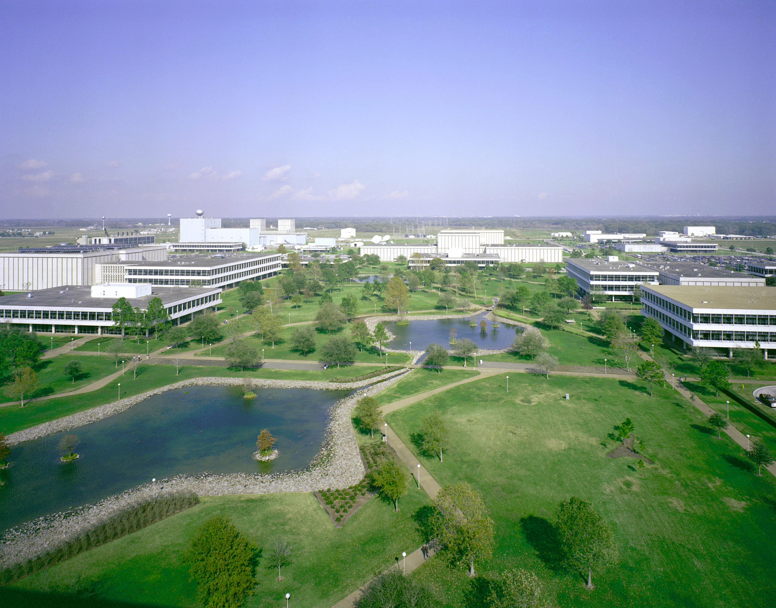 Aerial view of a NASA campus with multiple large buildings surrounded by trees and parking lots.
