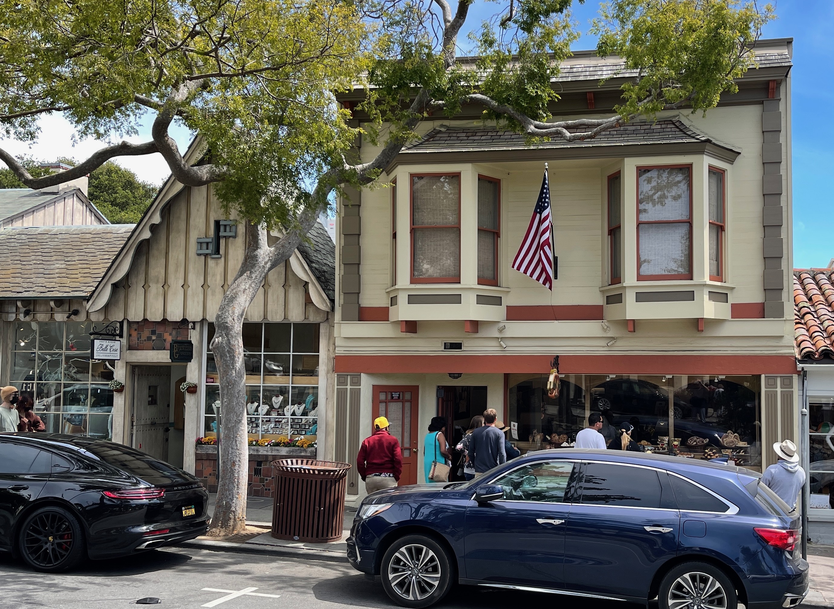 Two-story Victorian commercial building with an American flag on a downtown street with pedestrians.