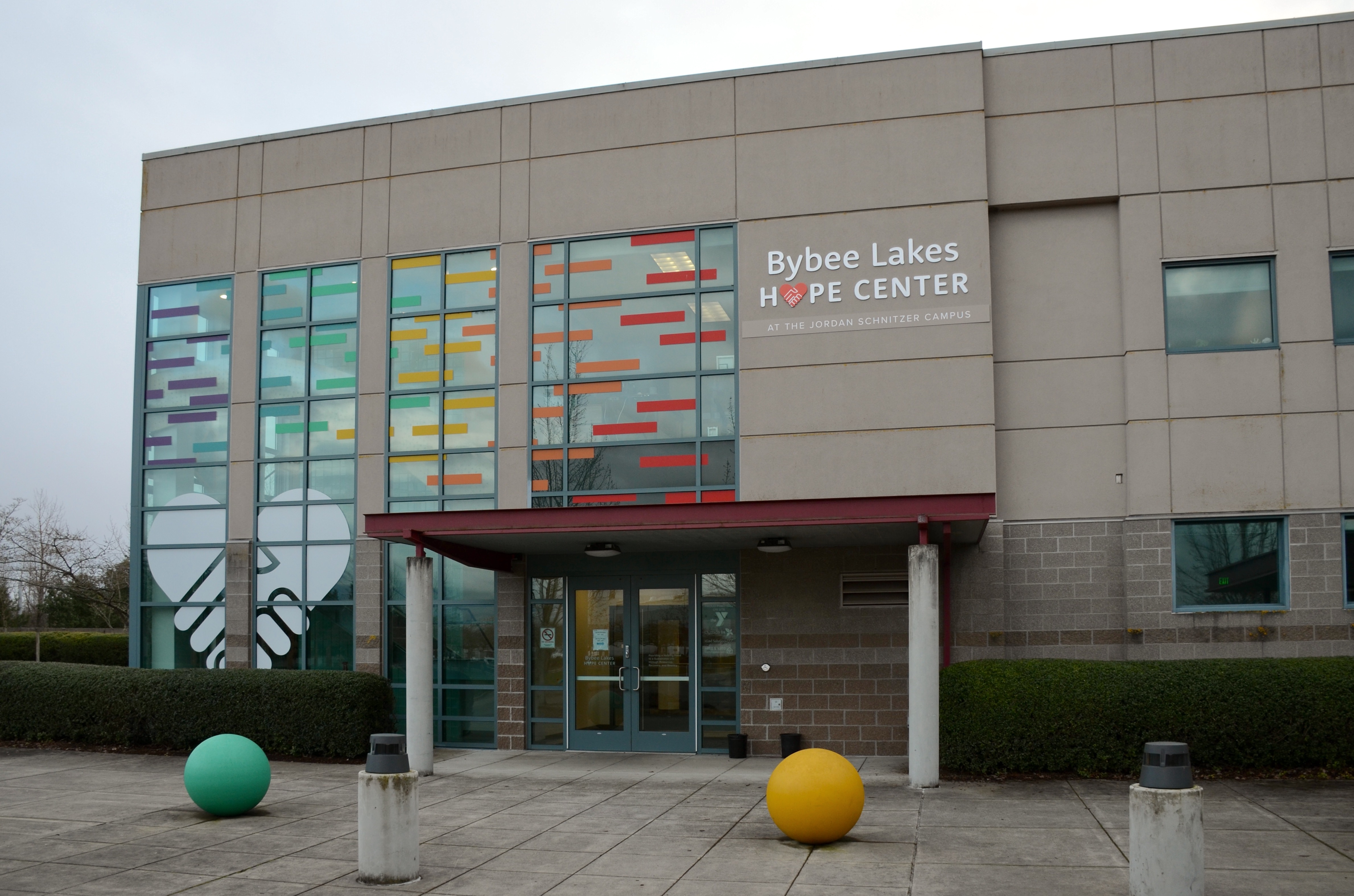 Entrance of a large institutional building repurposed as a homeless shelter with colorful panels.