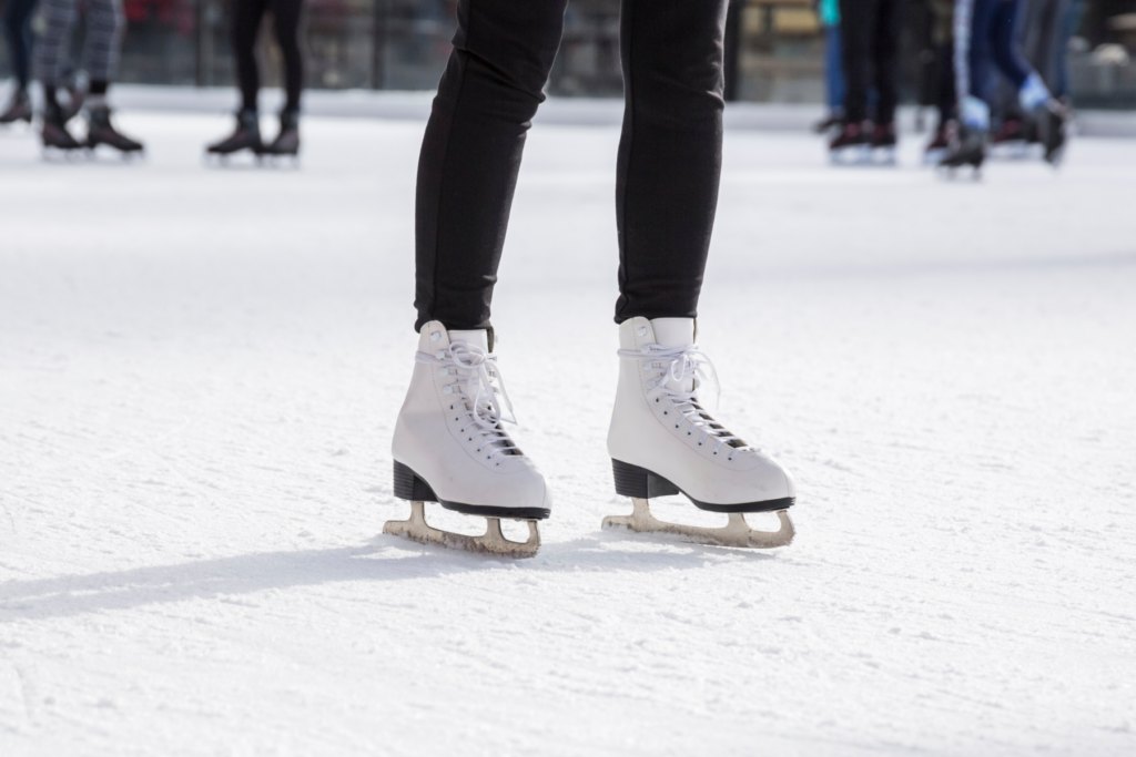 Close-up of white lace-up figure skates on an ice rink surface.