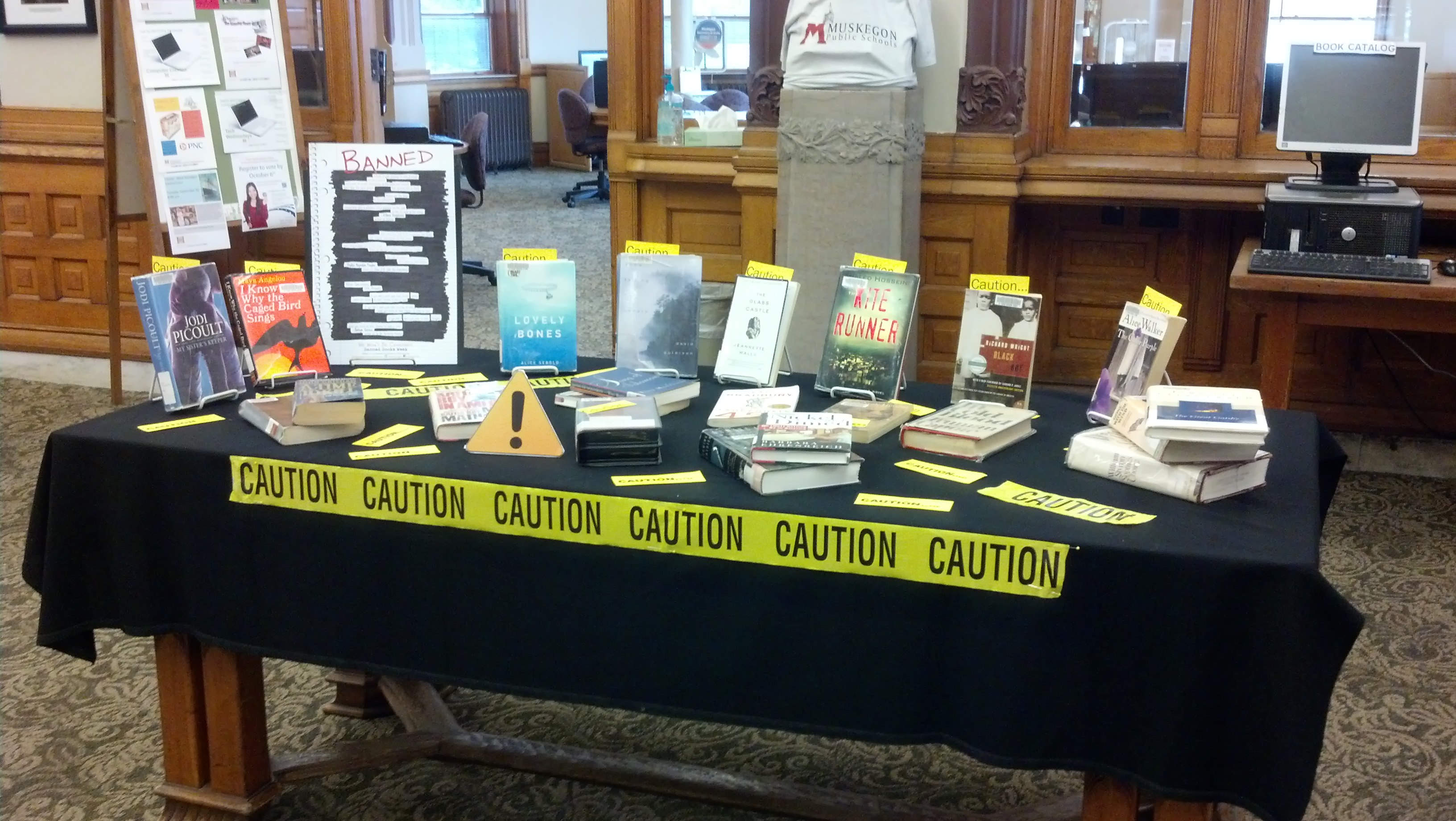 Books arranged on a table with yellow caution tape stretched across the front.