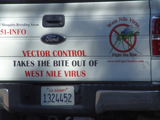 Rear of a white government truck with West Nile Virus mosquito control decals and a Fight the Bite graphic.