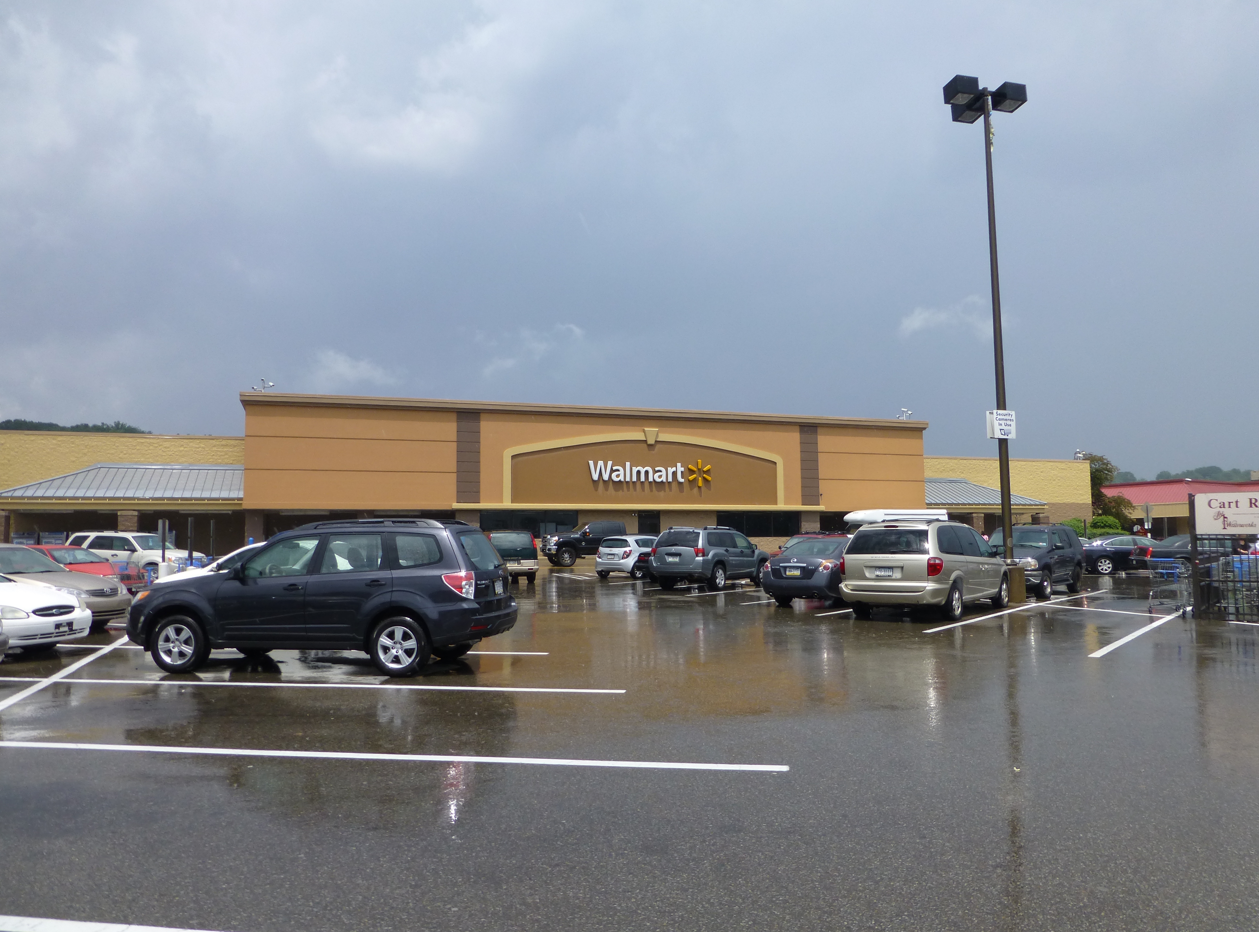 Walmart store exterior with a wet parking lot and overcast sky.