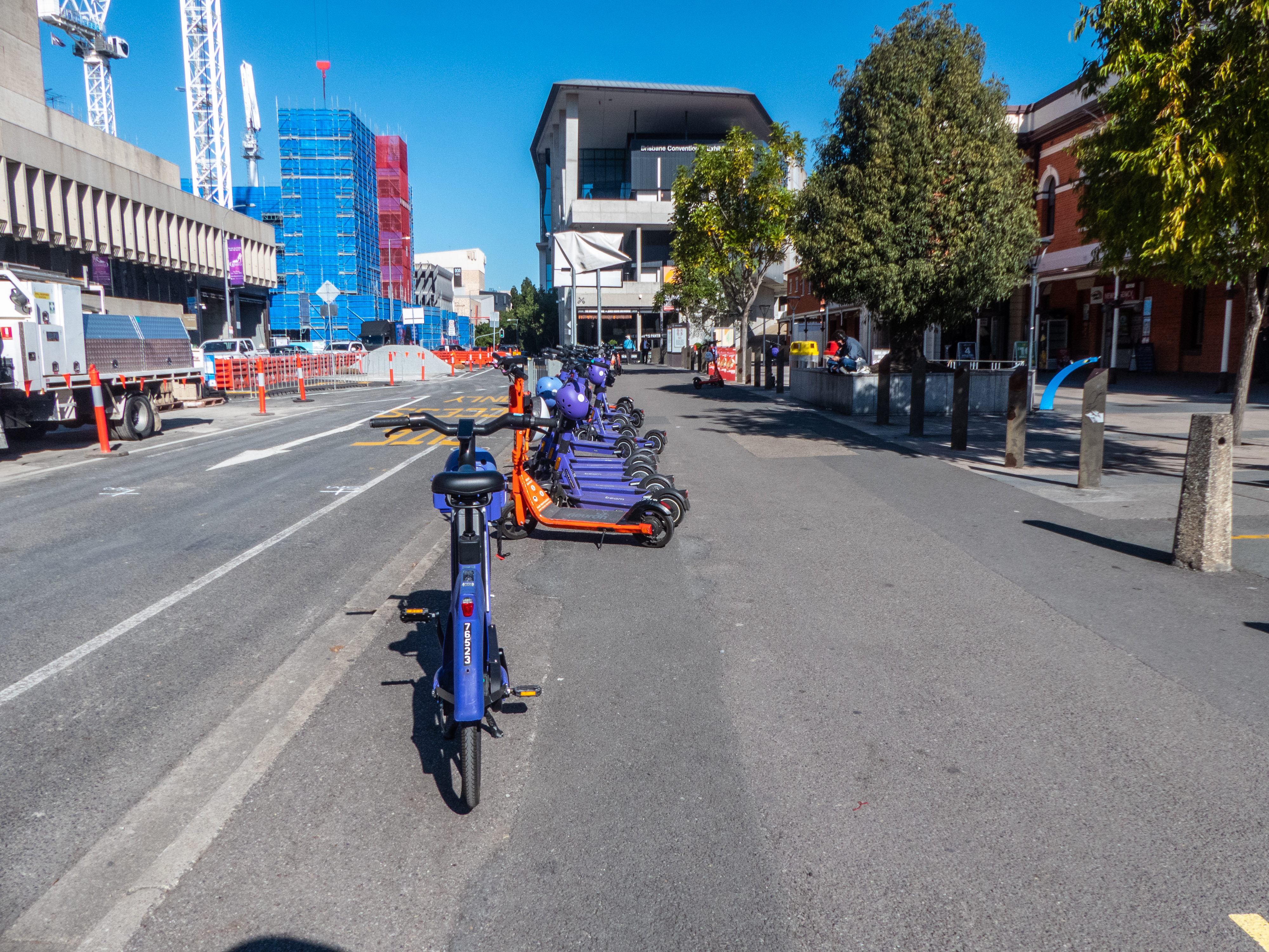 A row of shared e-bikes and e-scooters parked along an urban street.
