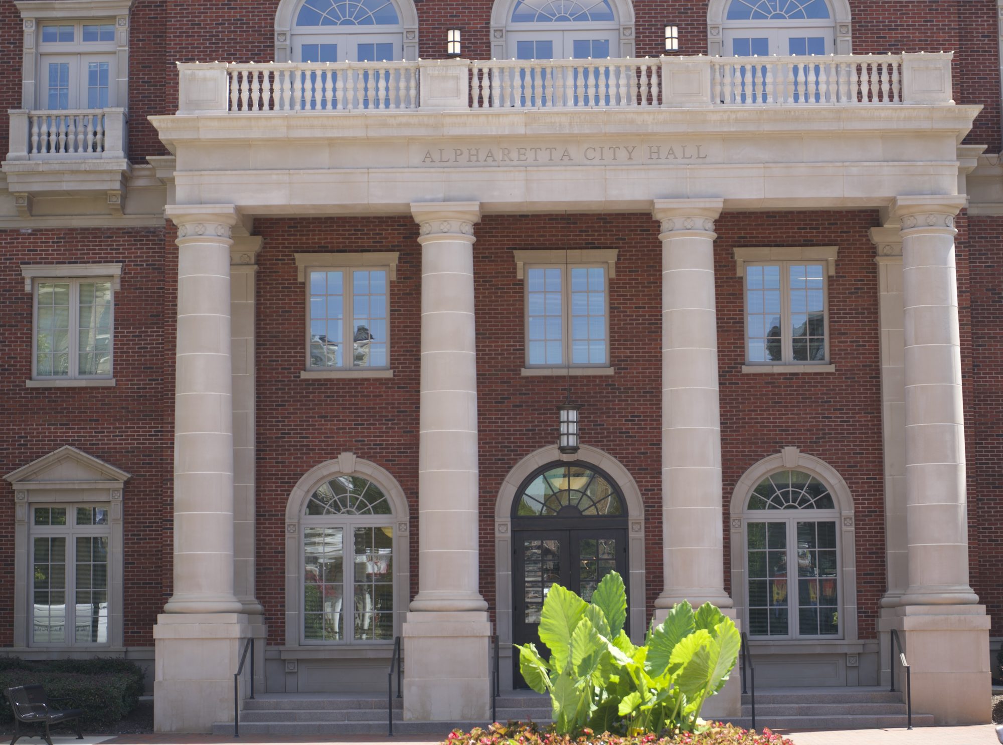 Red-brick neoclassical building with white columns and stone city hall inscription above entrance