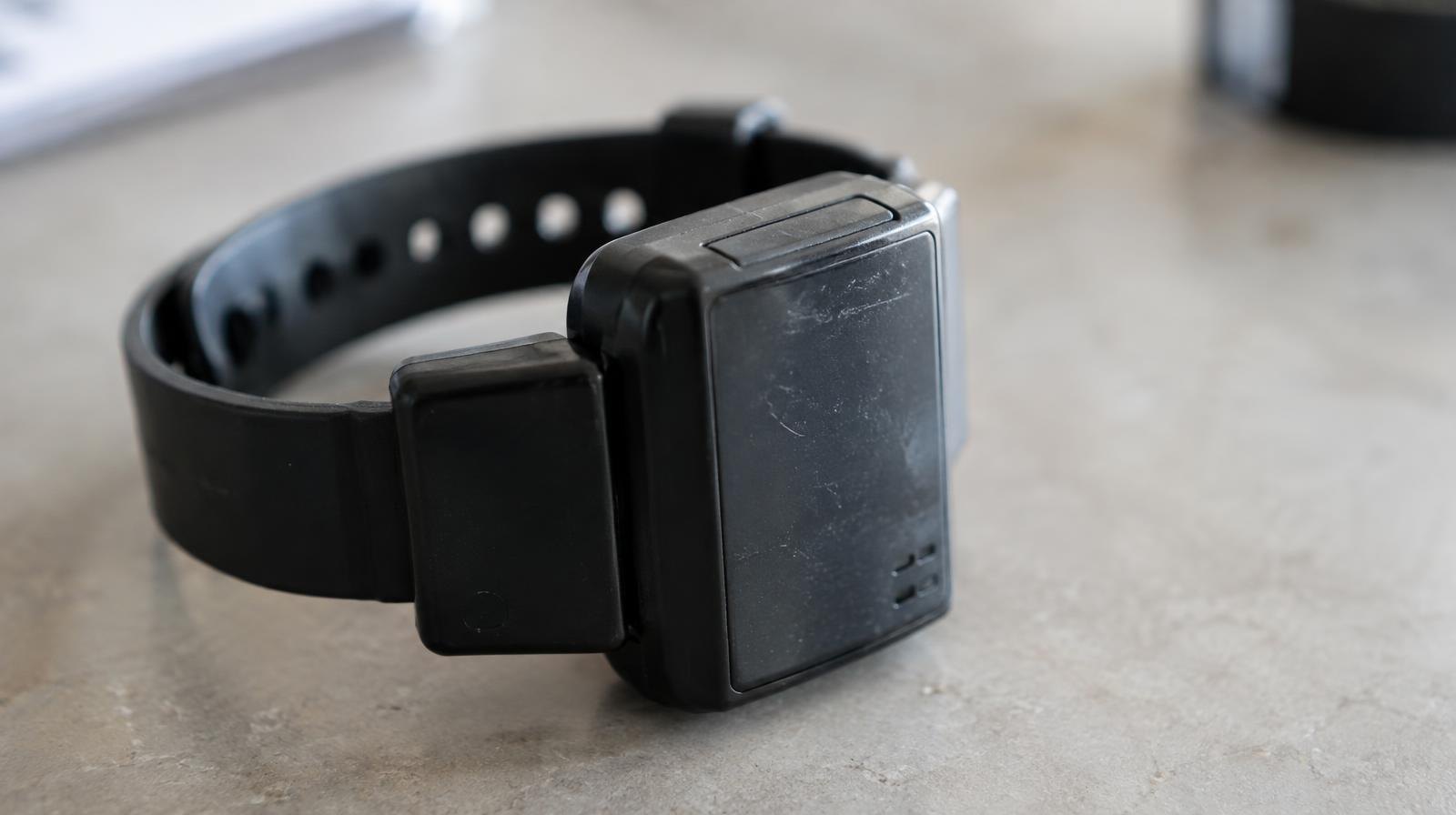 GPS ankle monitoring bracelet resting on a plain surface.