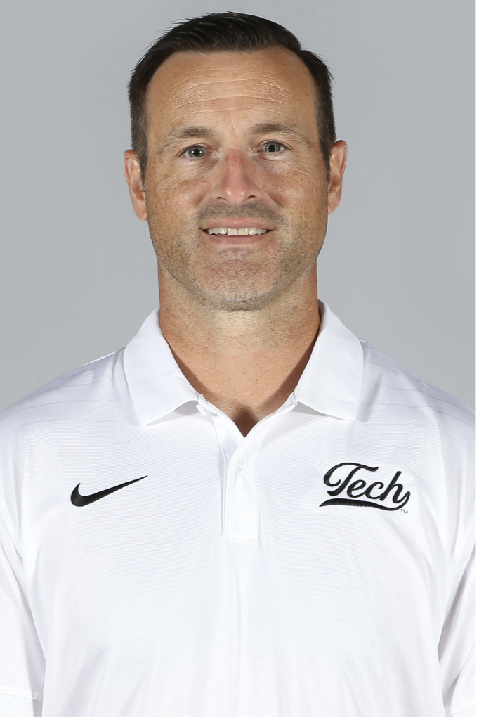 Michigan Tech head football coach Dan Mettlach poses for a headshot in a white Tech polo shirt.