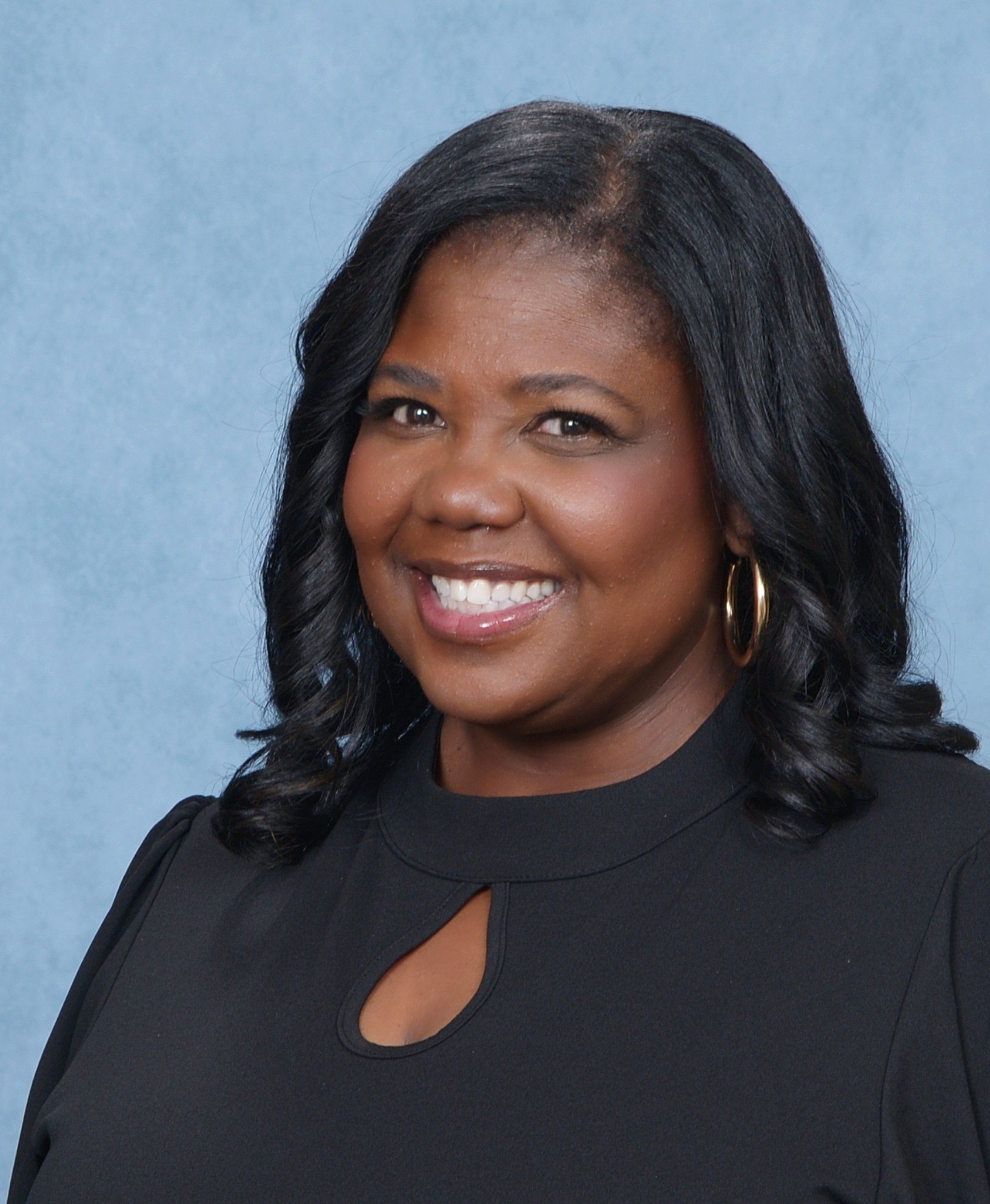Woman in black top smiling in a professional studio portrait.