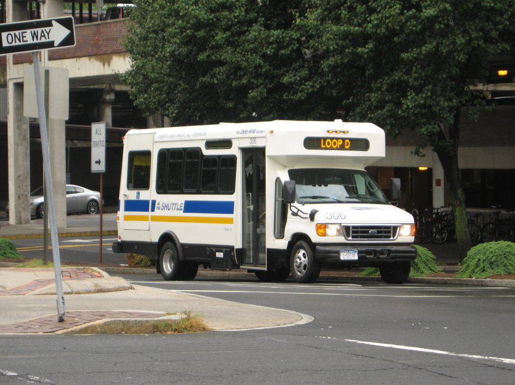 Small white Bee-Line shuttle bus at a street corner with a Loop D destination sign.