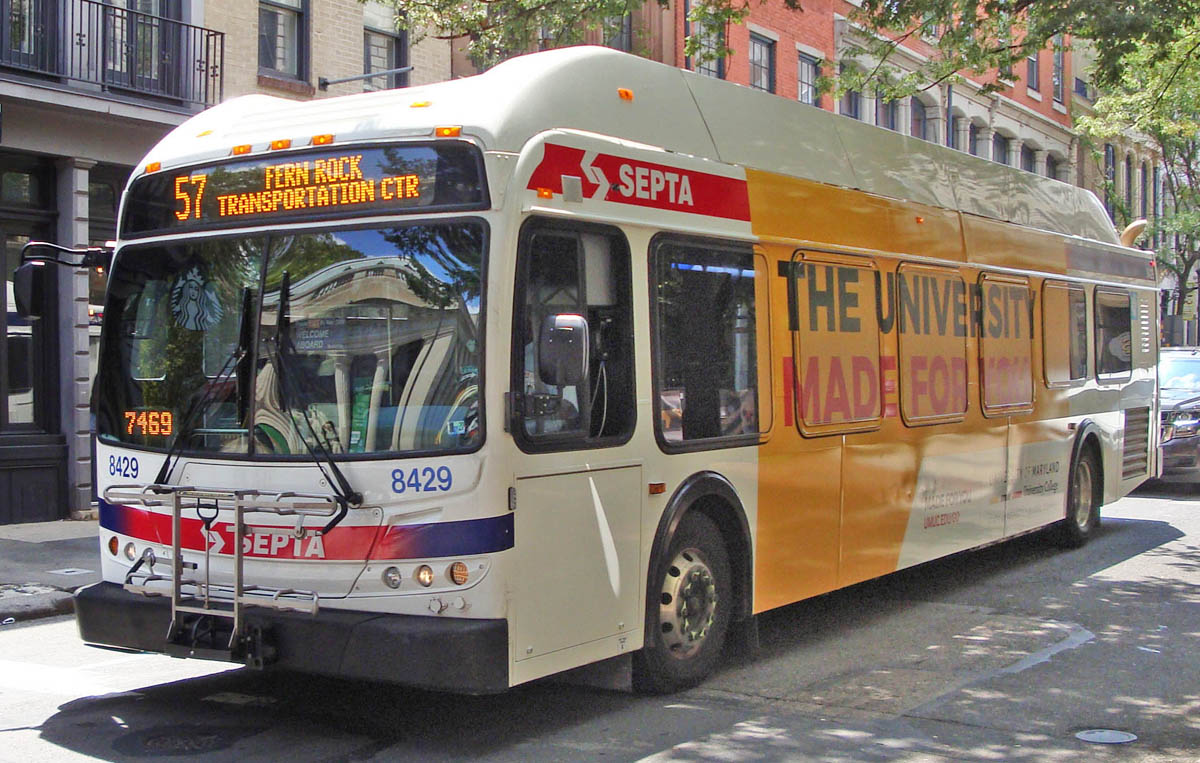 A white SEPTA bus displaying a route number stopped on a tree-lined city street.