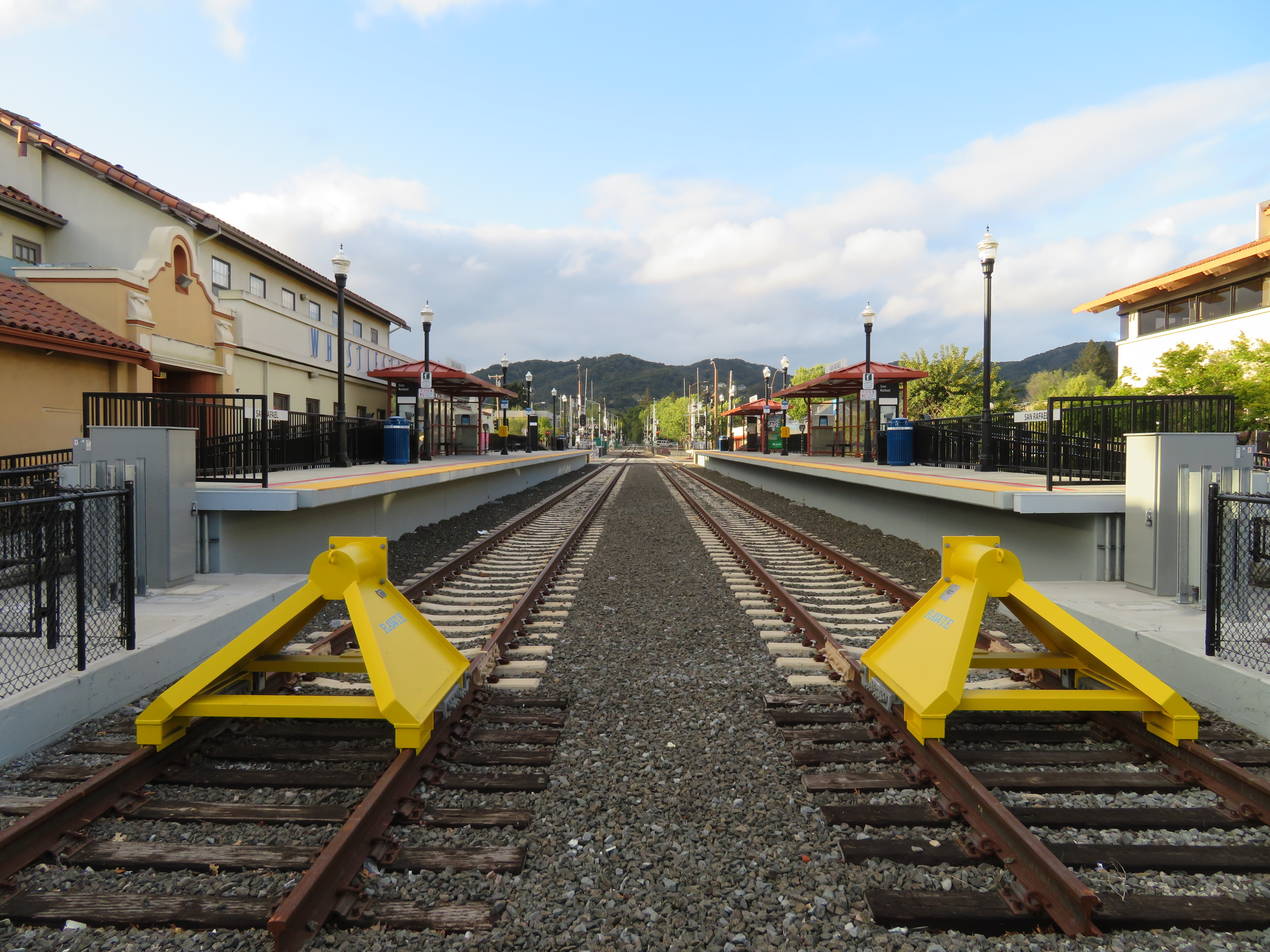 Rail tracks and platforms at the San Rafael Transit Center, with yellow buffer stops in the foreground.
