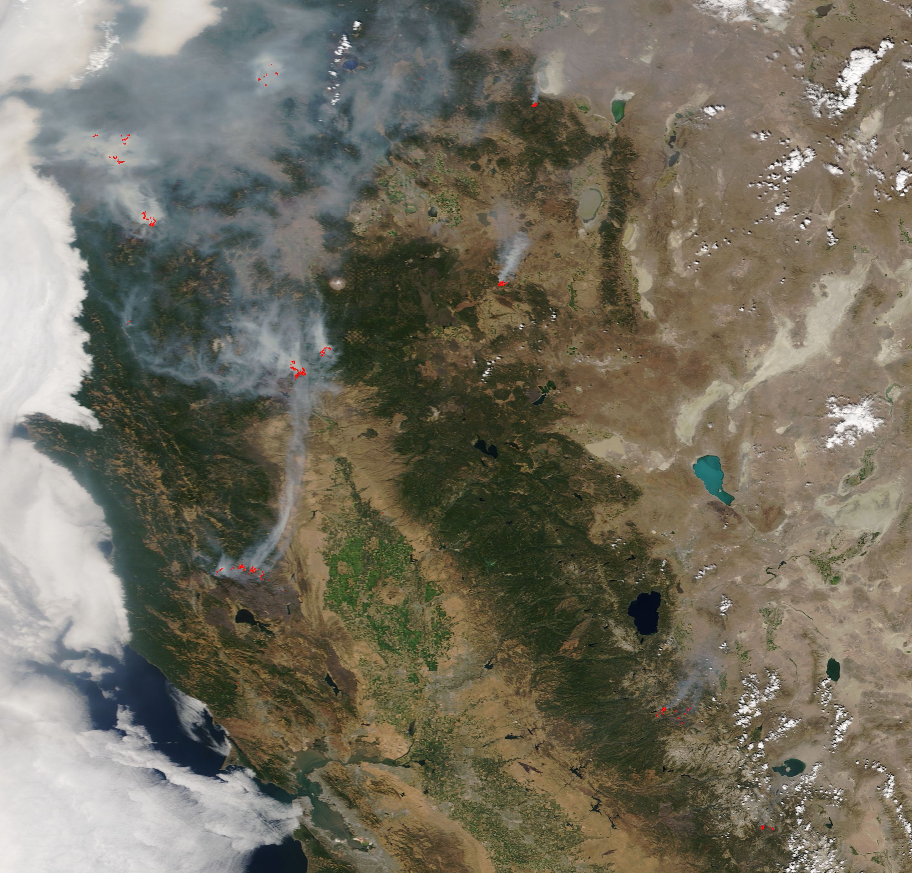 Satellite image of the western United States with red wildfire hotspots and gray smoke plumes.