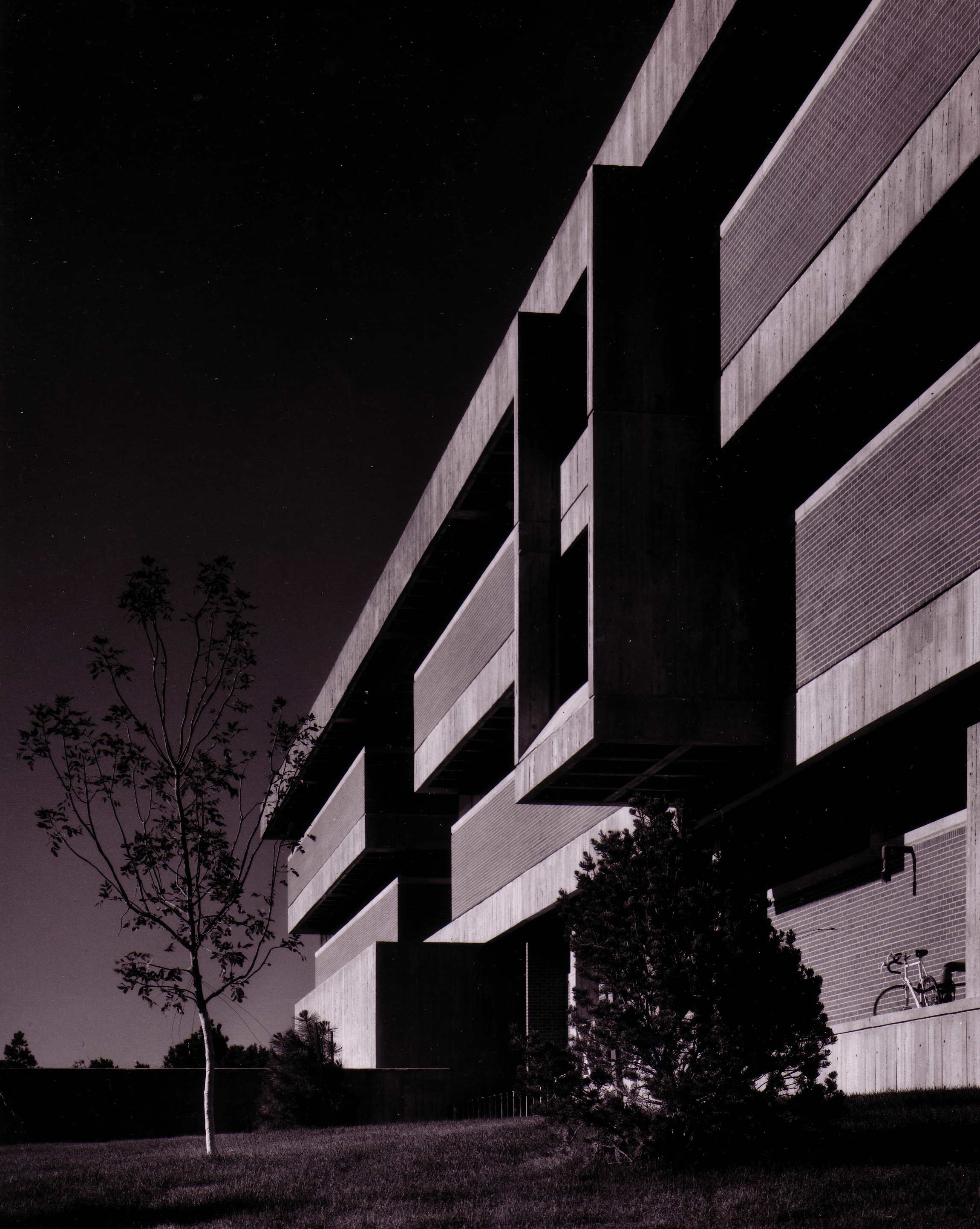 Modernist multi-story school building exterior photographed at night in black and white.