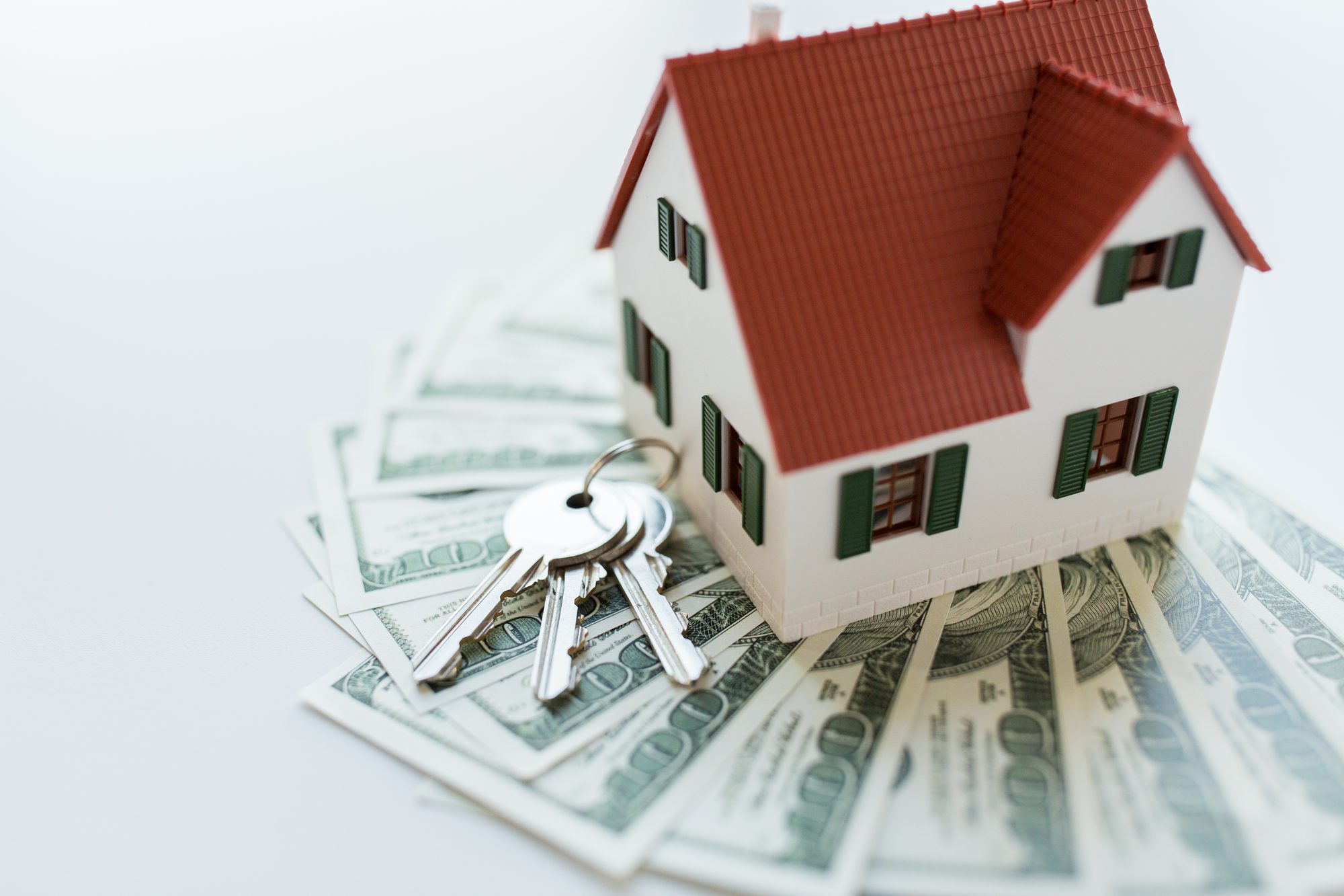 mortgage, investment, real estate and property concept - close up of home model, dollar money and house keys