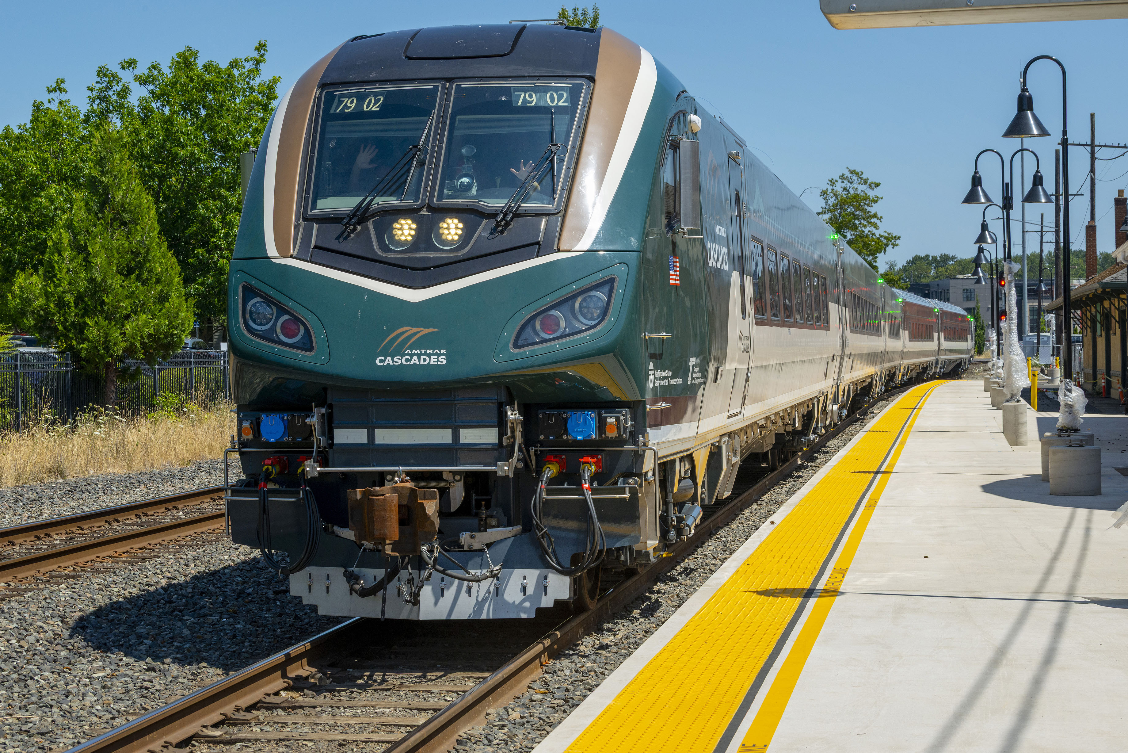 Front of a green and gold Amtrak Cascades Airo train at a station platform.
