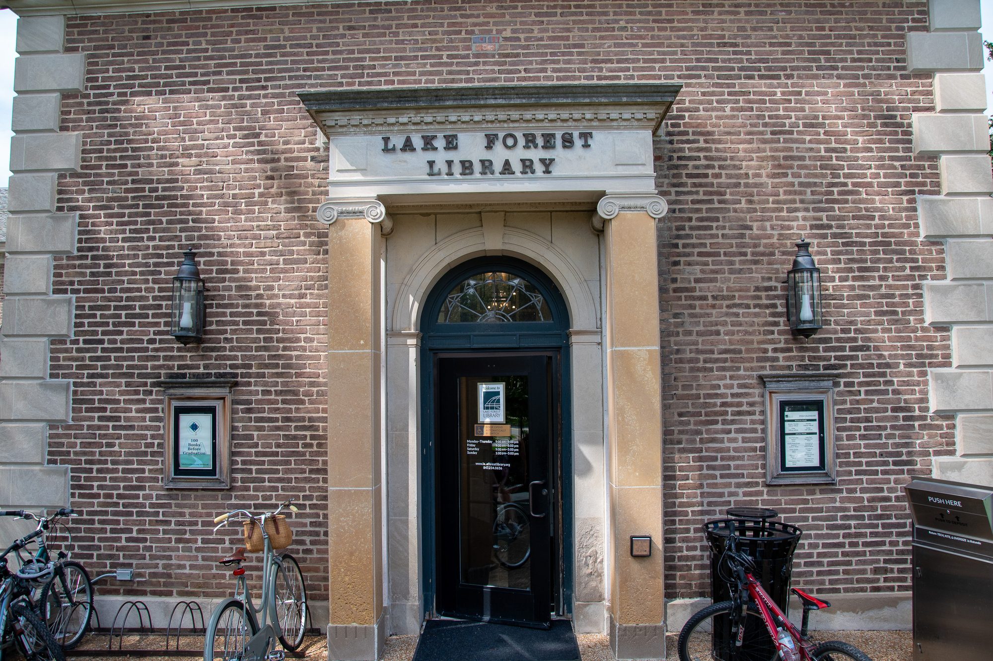 Brick library building entrance with arched doorway and wall-mounted lanterns