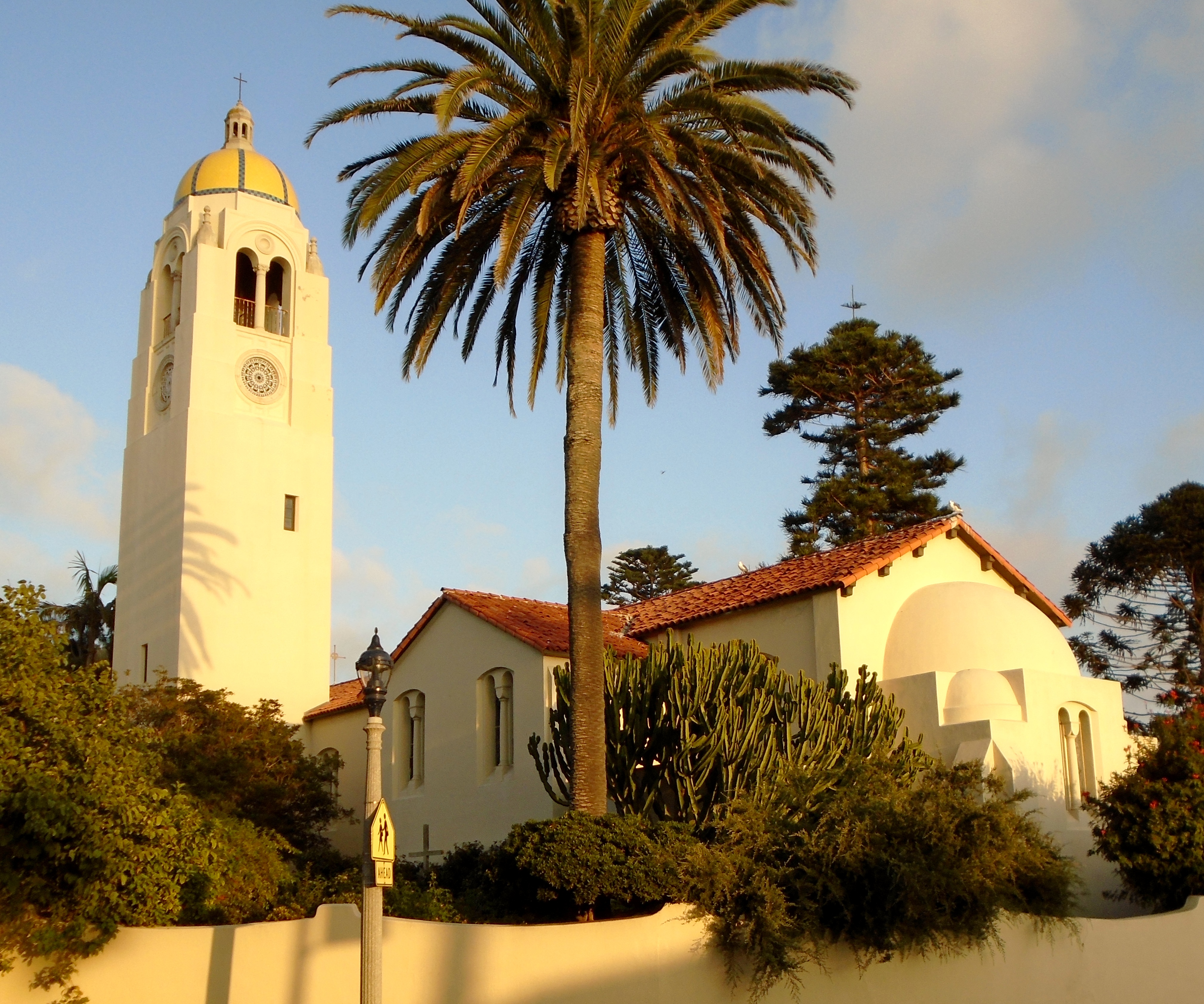 White bell tower with gold dome and palm tree at a La Jolla school campus.