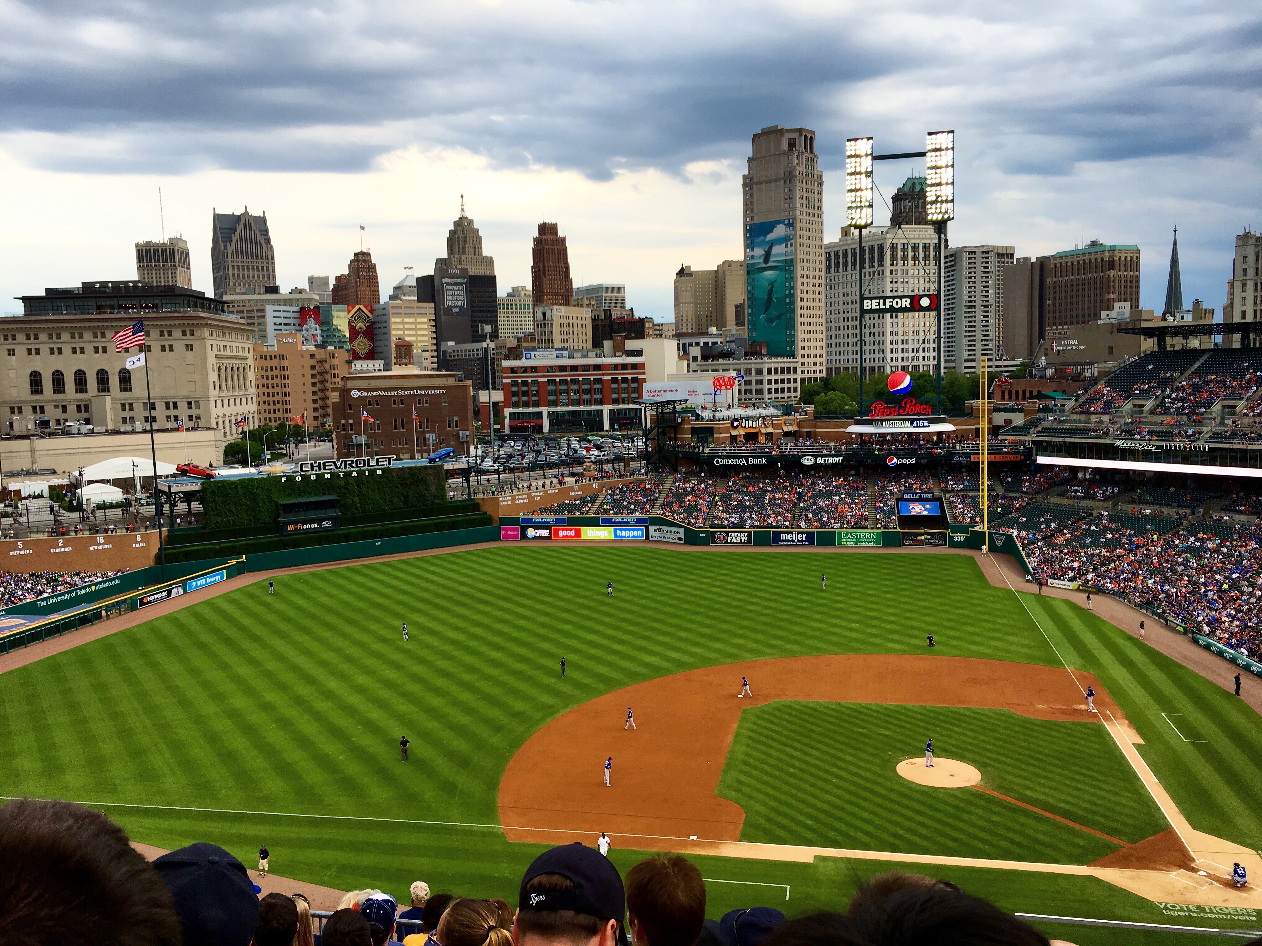Aerial view of a baseball stadium during a game with a city skyline in the background.